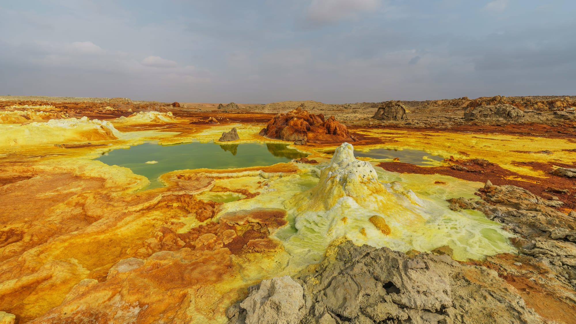 A surreal landscape of yellow, green and orange mineral crusts and acid pools