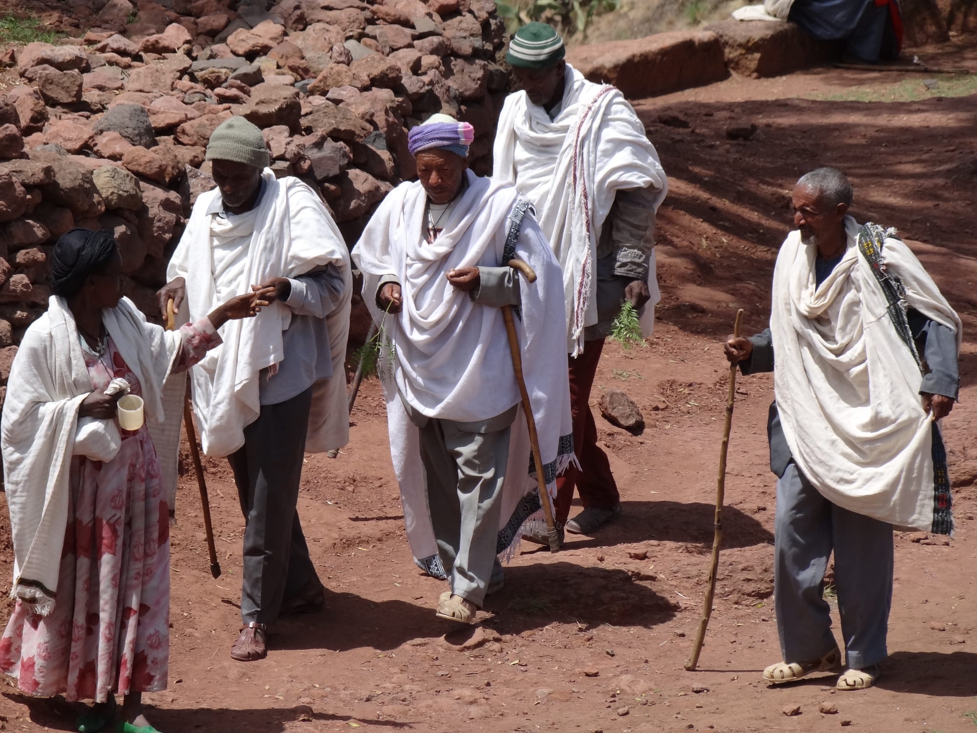 A group of pilgrims in white shawls gathered outside a rock-hewn church