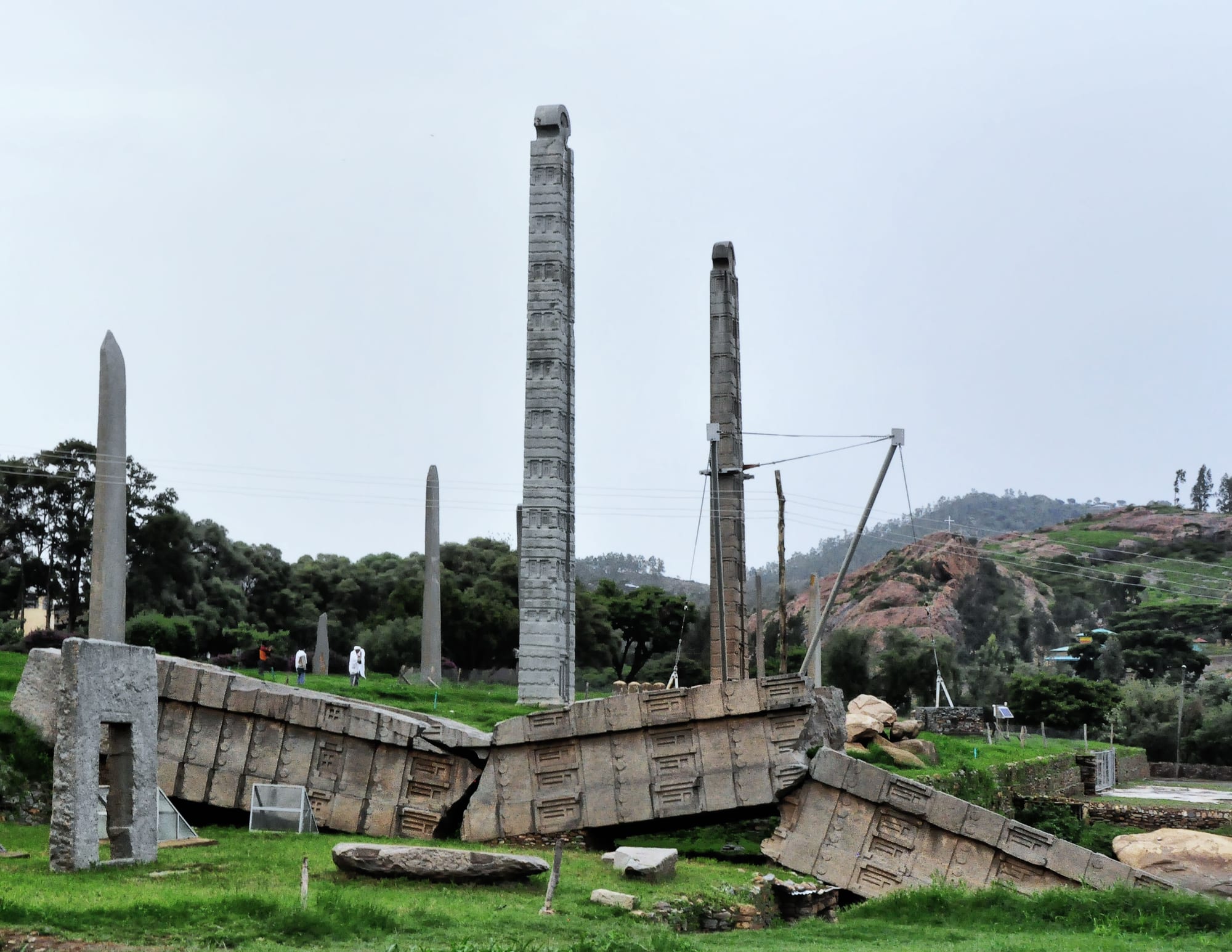 Towering carved granite obelisks, one standing and one fallen and broken, on open ground