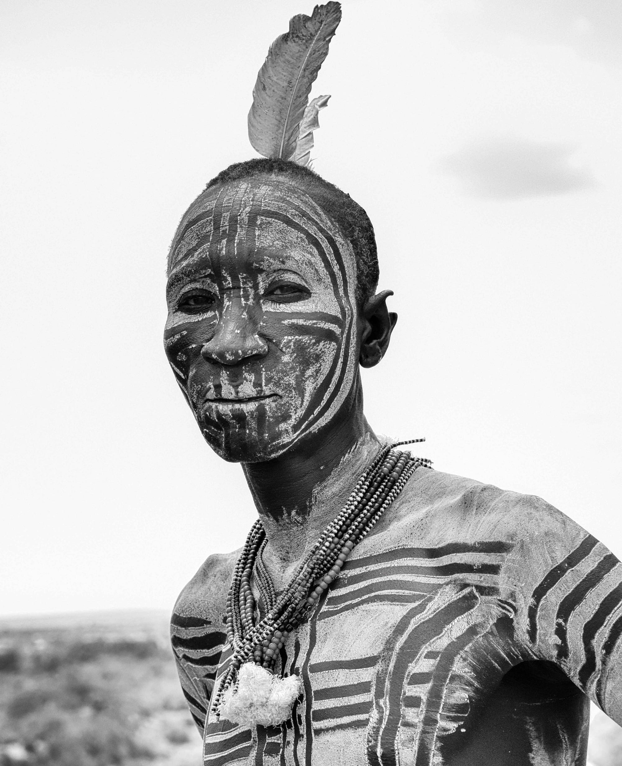 A man of the Karo people with painted face and body markings and a feather headdress