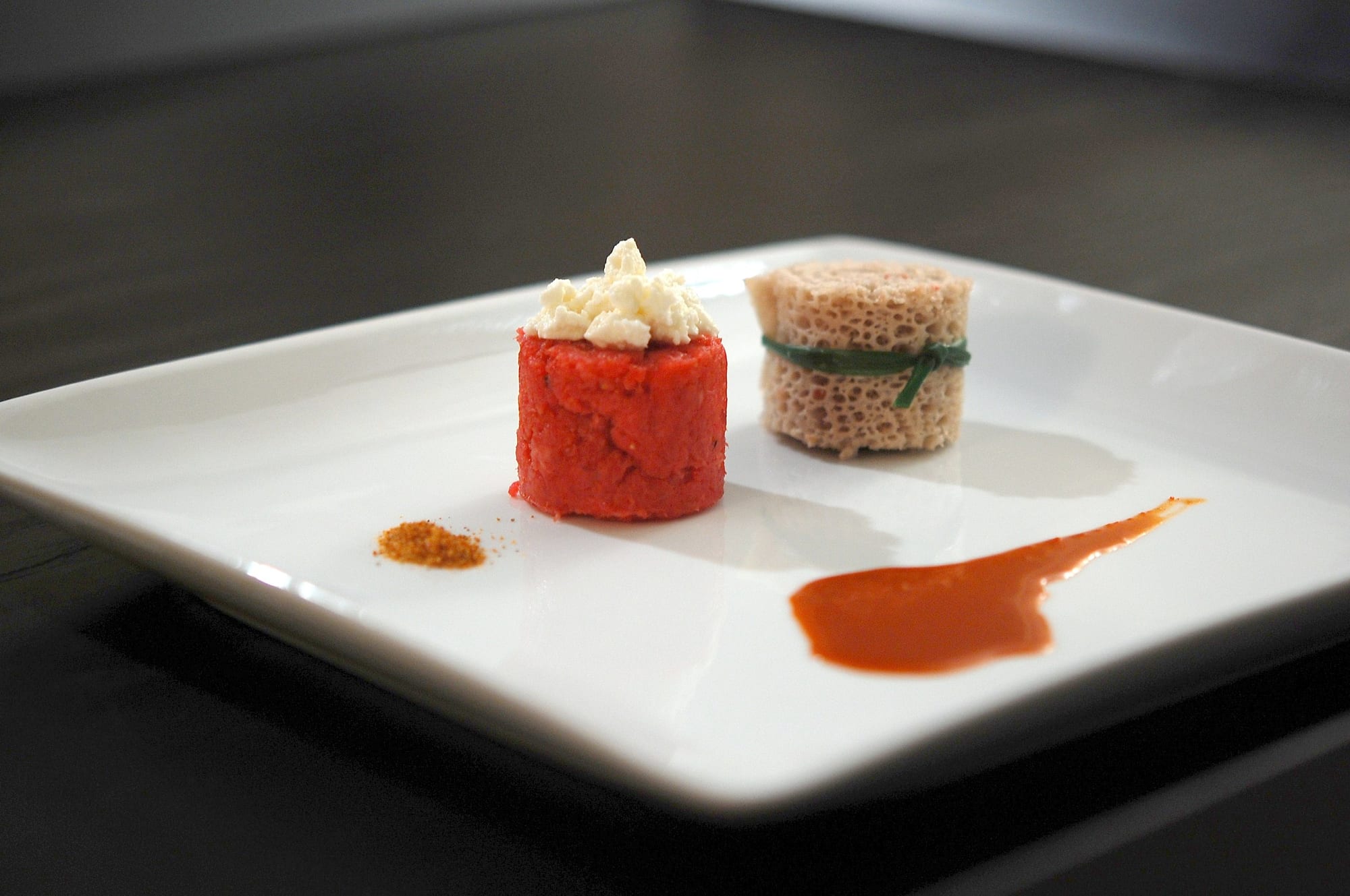 A mound of minced raw beef beside cheese, flatbread and small dishes of sauce