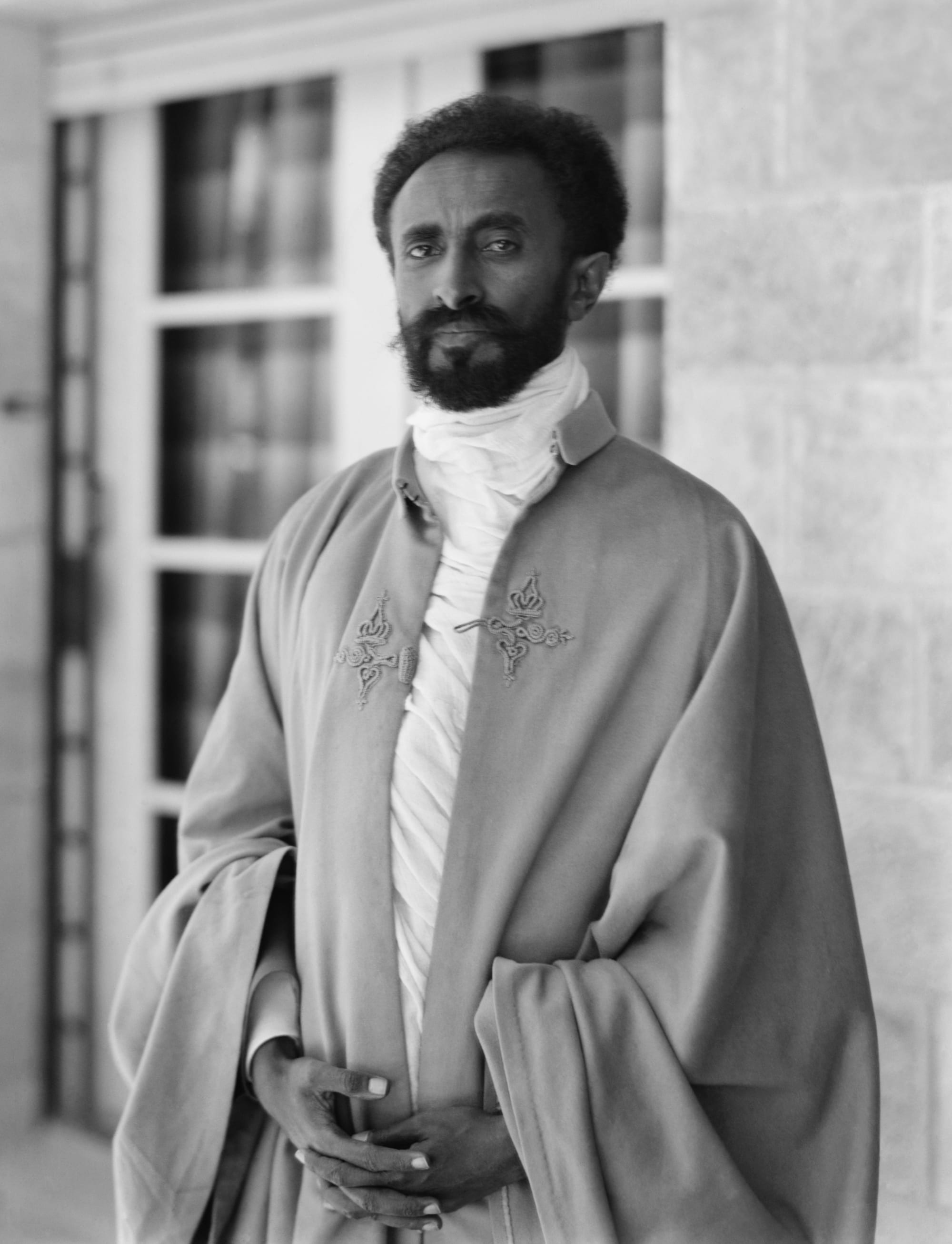 Emperor Haile Selassie in a military uniform and cape, standing formally for a portrait