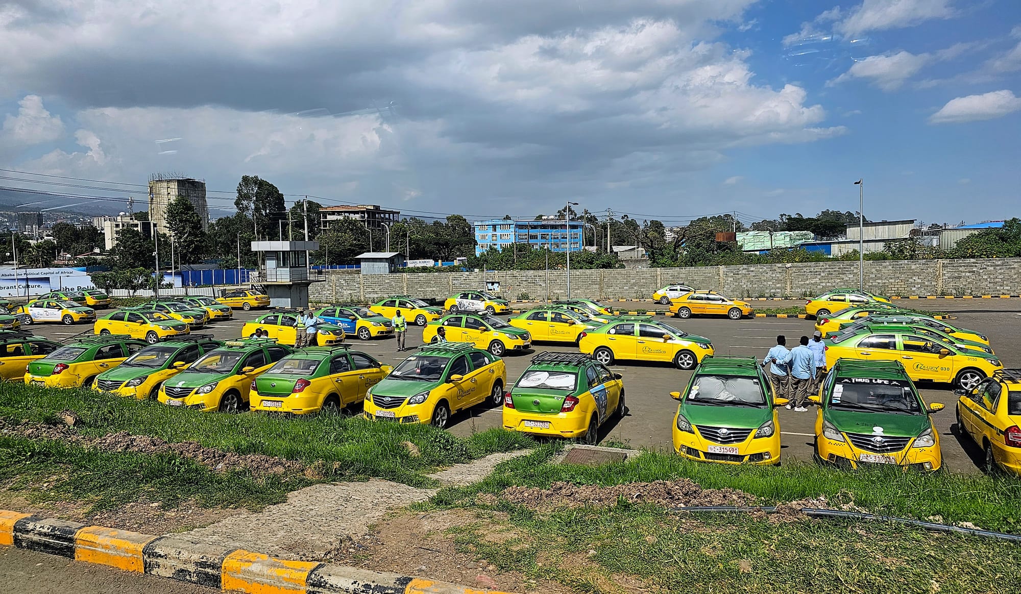 Blue-and-white minibus taxis and pedestrians on a busy Addis Ababa street with high-rise buildings behind