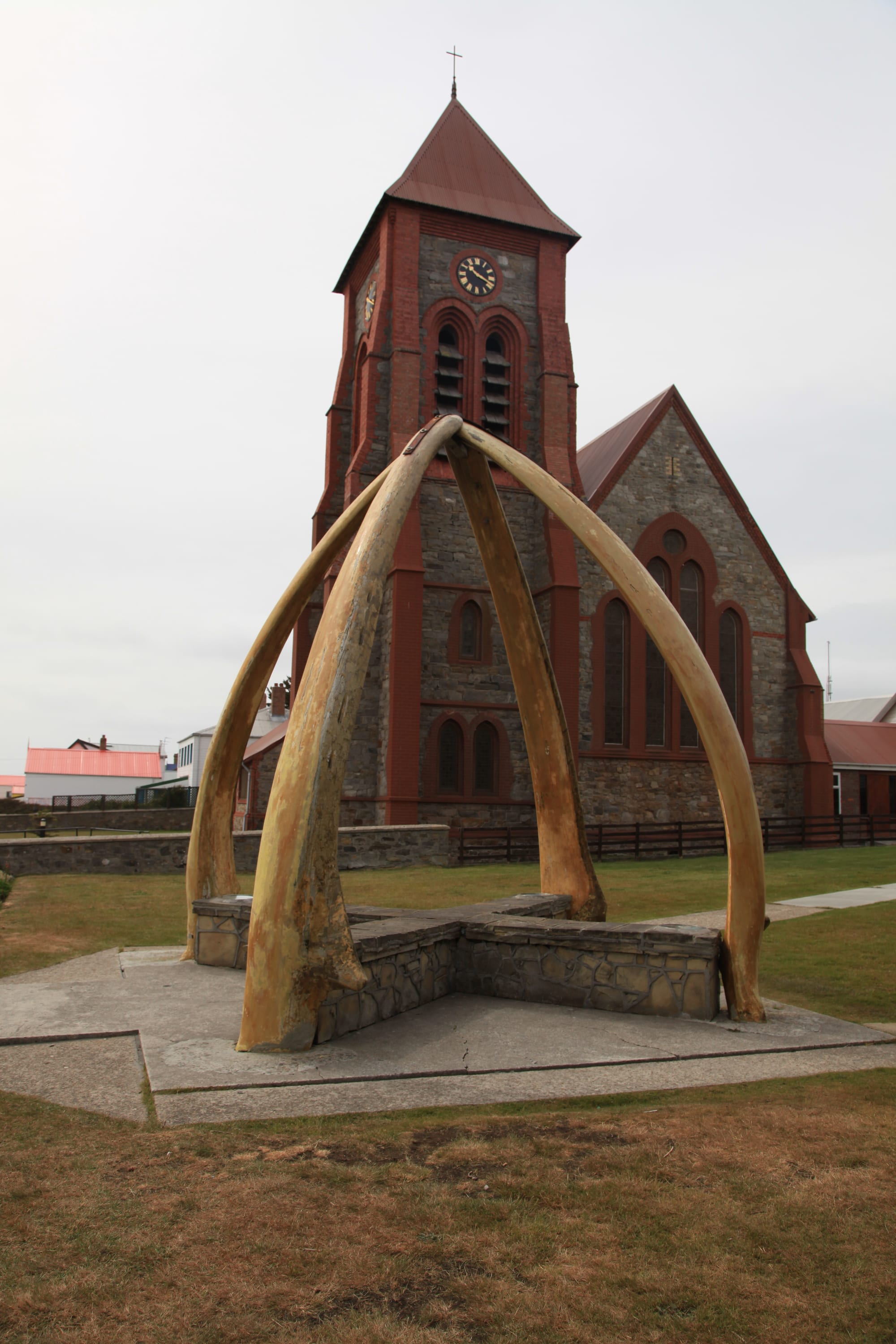 A whalebone arch in front of the red-brick and stone Christ Church Cathedral
