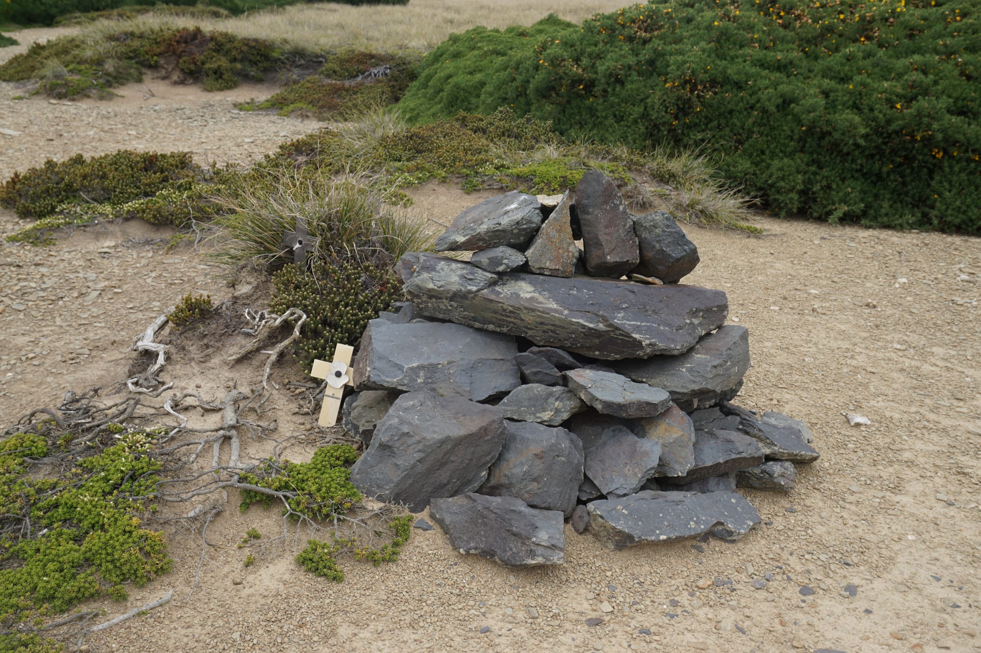 A simple cairn and cross memorial on open moorland with a peat-cutting scar