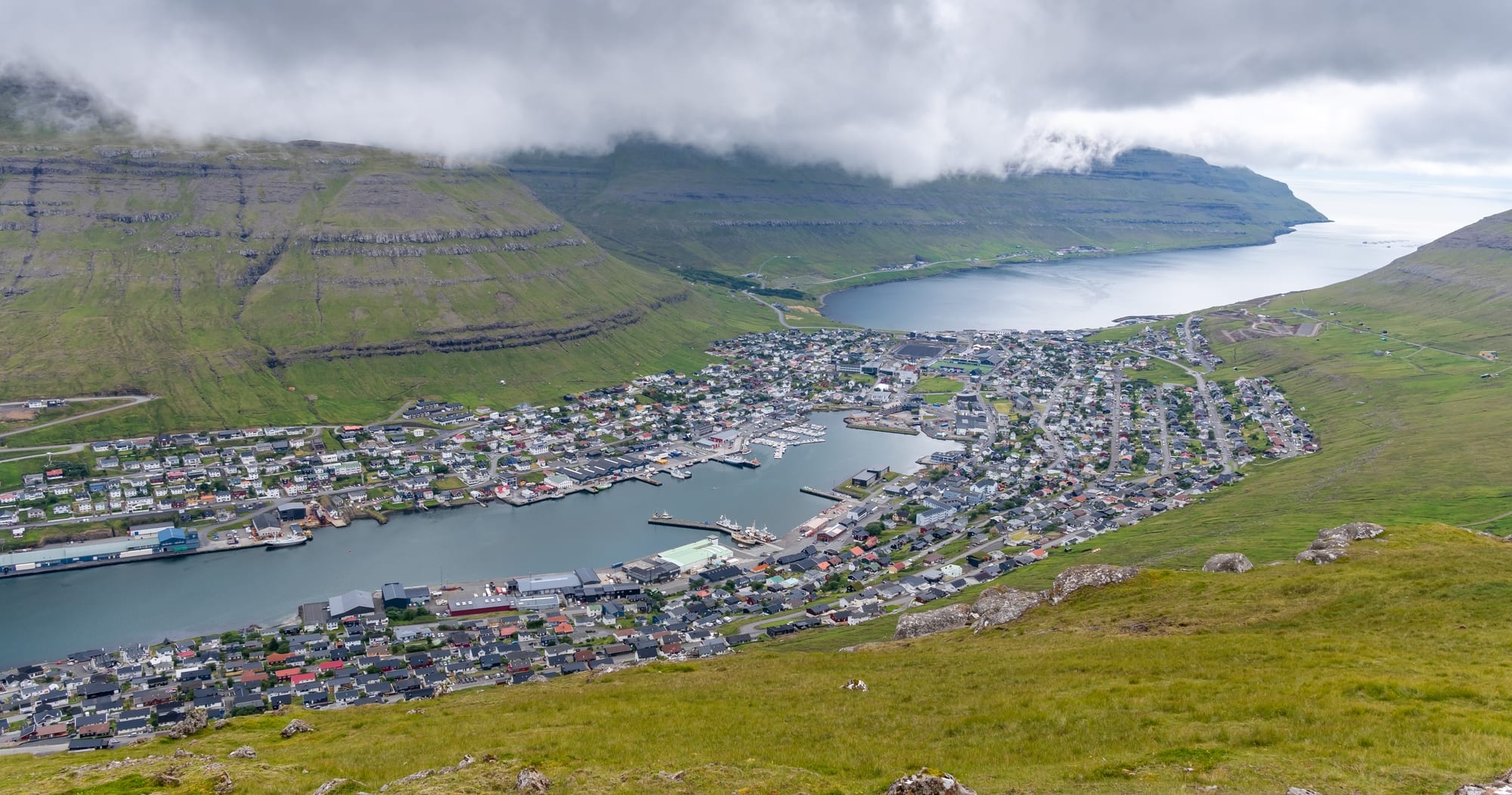 A fishing town wrapped around a narrow harbour inlet between steep green mountains