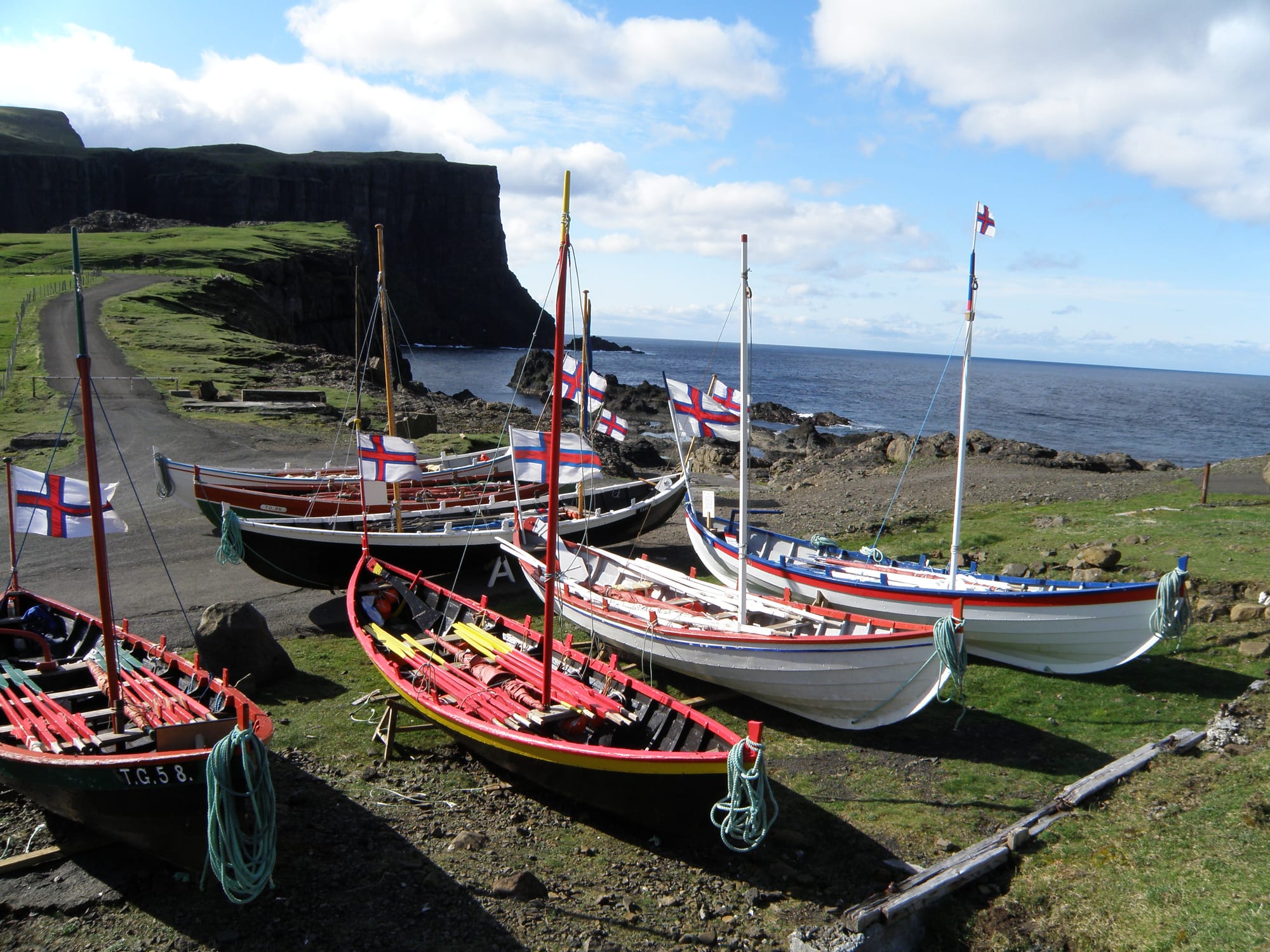 Wooden open boats with high prows drawn up on a slipway in a Faroese village
