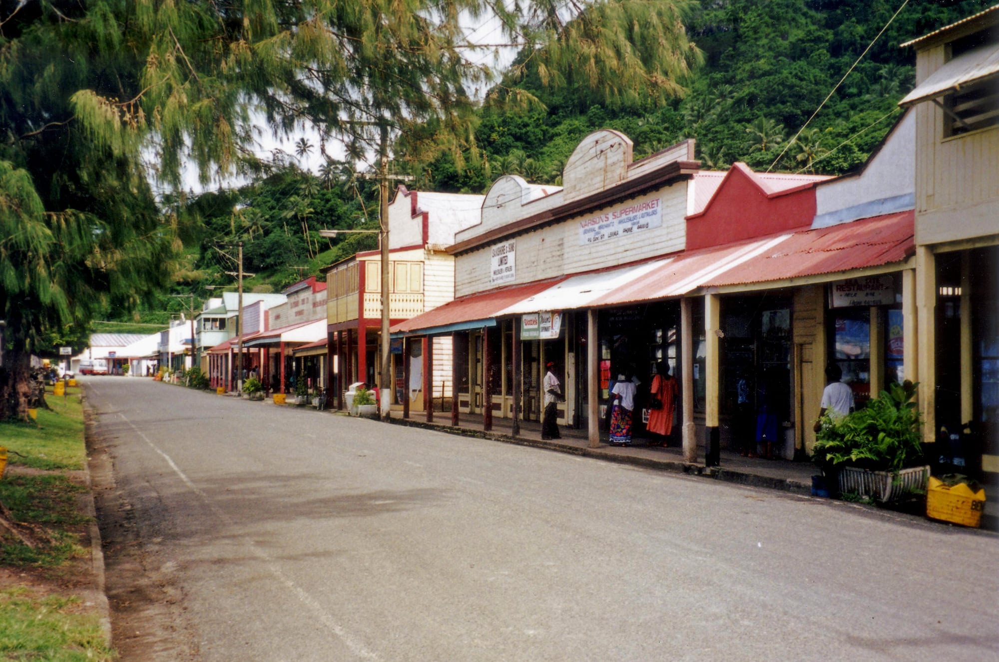 A row of weathered timber colonial shopfronts along a seafront street