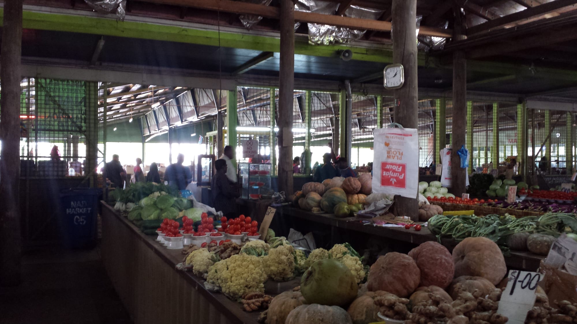 The covered interior of Nadi Municipal Market in Fiji, with long tables piled with cauliflower, tomatoes, pumpkin, cabbage and root vegetables