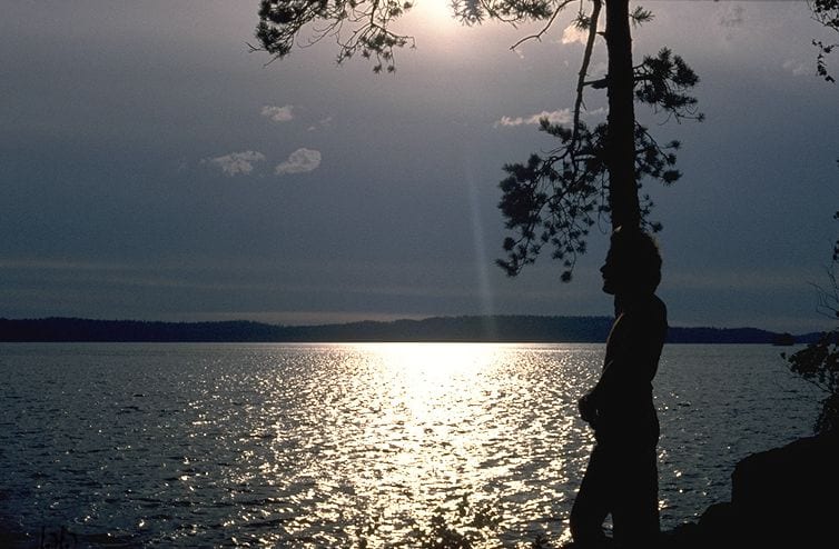 A still lake at sunset with forested islands in silhouette