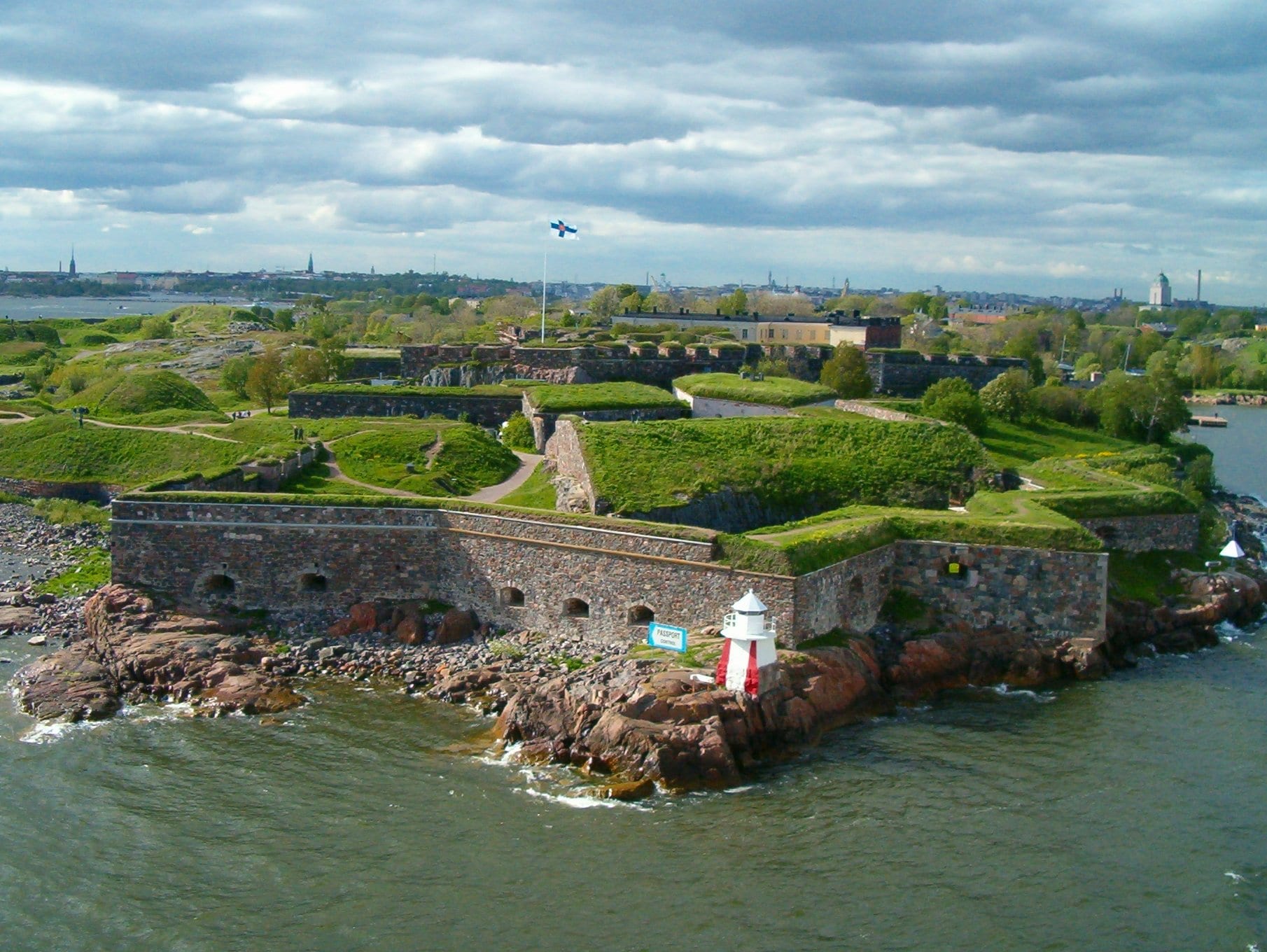Grass-topped stone ramparts and old cannon on an island, with the sea beyond