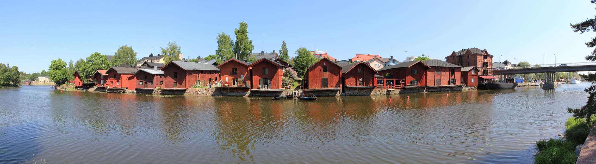 A row of ochre-red wooden storehouses along a river bank