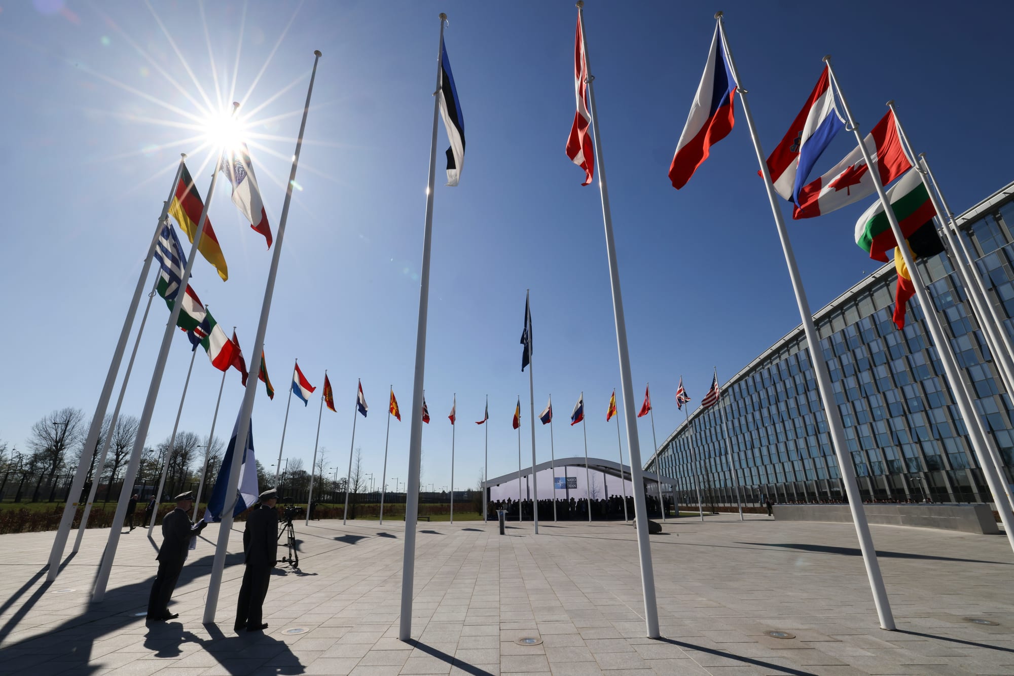 The blue-and-white flag of Finland being raised on a flagpole outside NATO headquarters