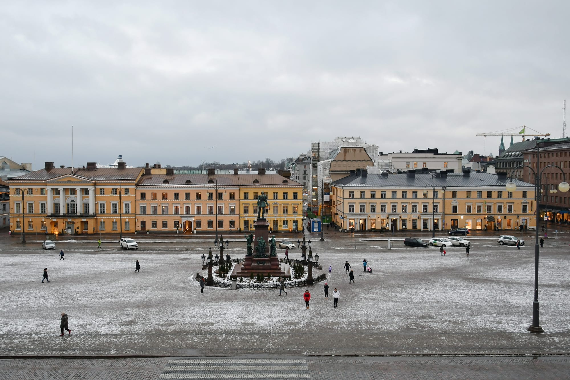 A white neoclassical cathedral with a green dome above a broad cobbled square in winter light