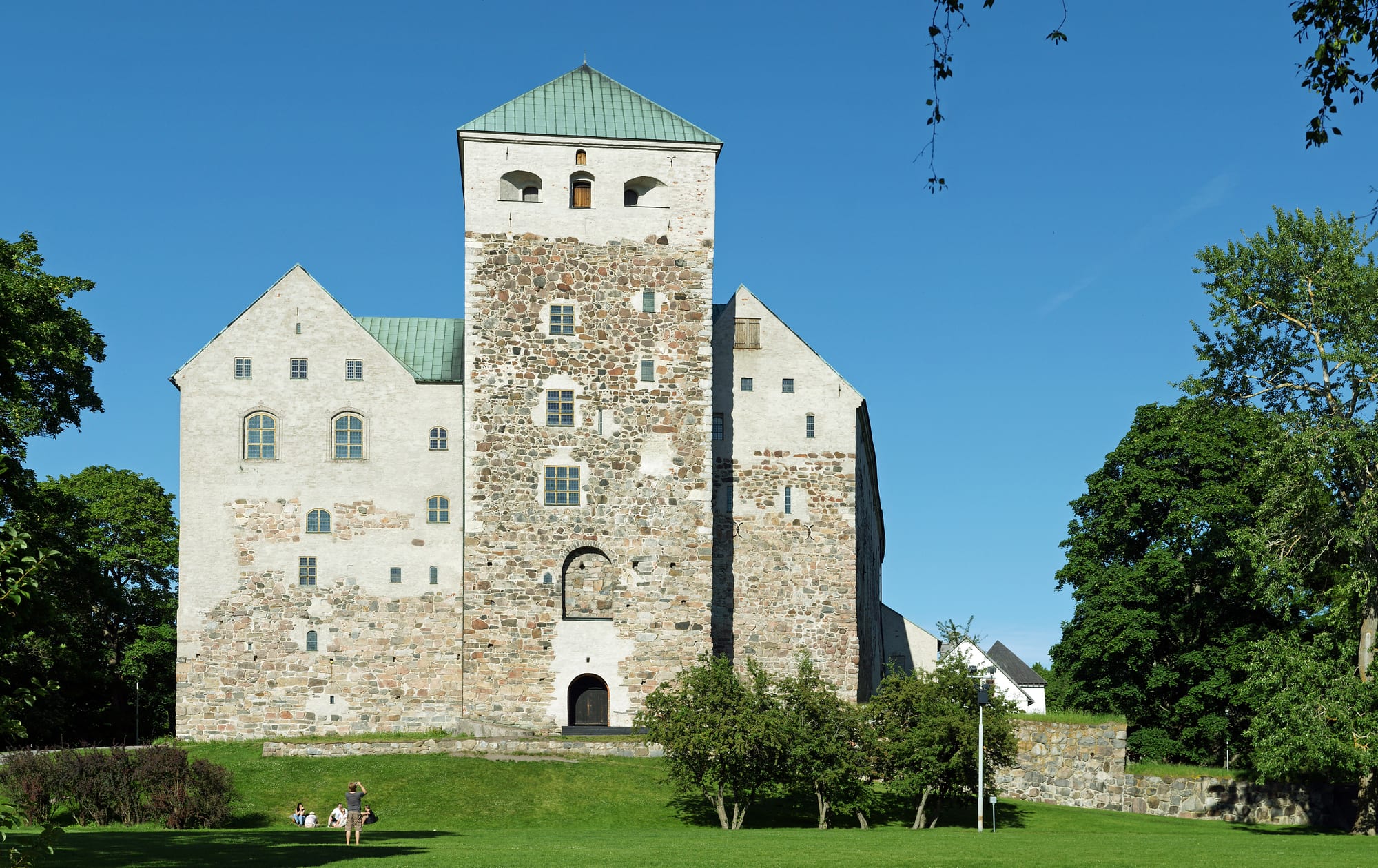 A large pale stone medieval castle with a square keep, beside a harbour