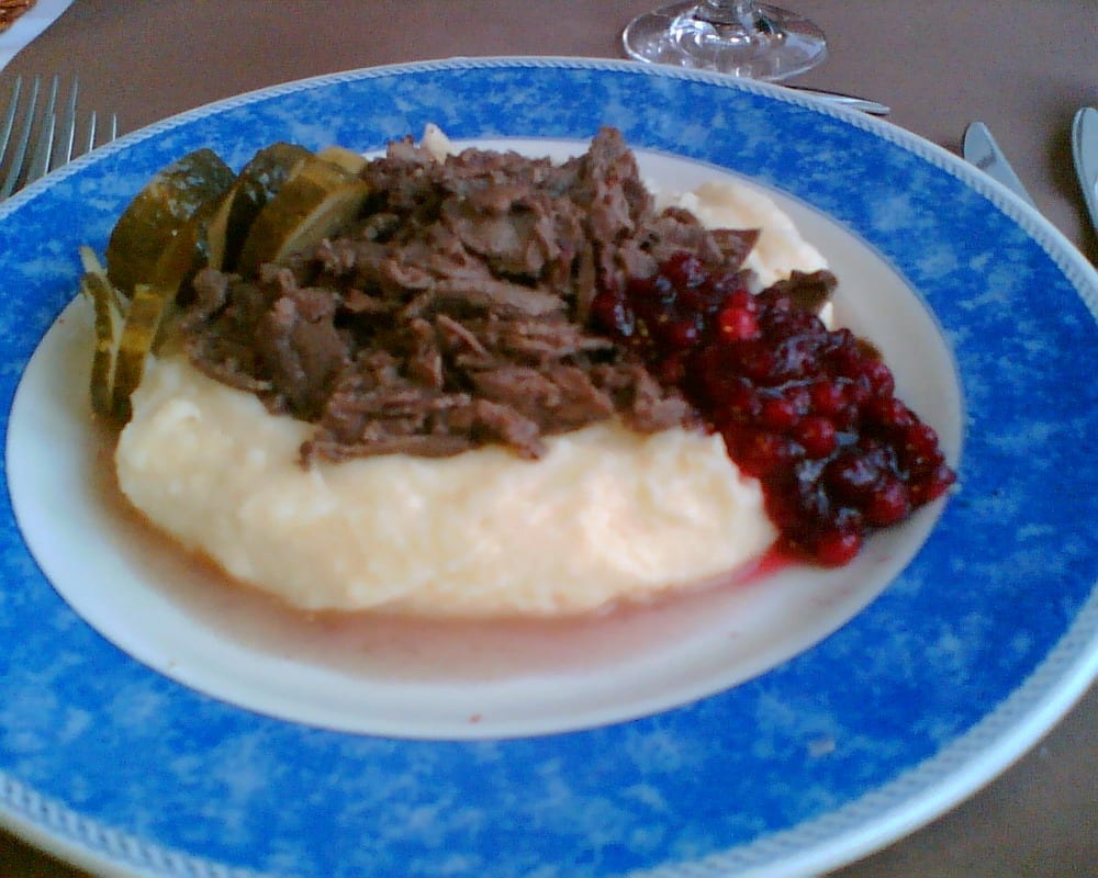 Thin strips of dark sautéed meat with mashed potatoes and lingonberries on a plate
