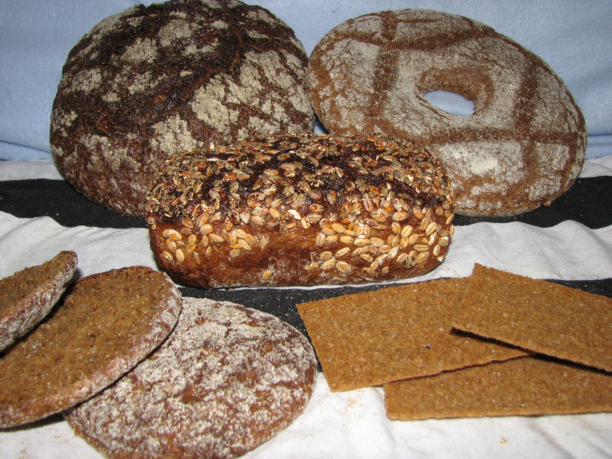 Several dark, round loaves and rings of bread laid out together