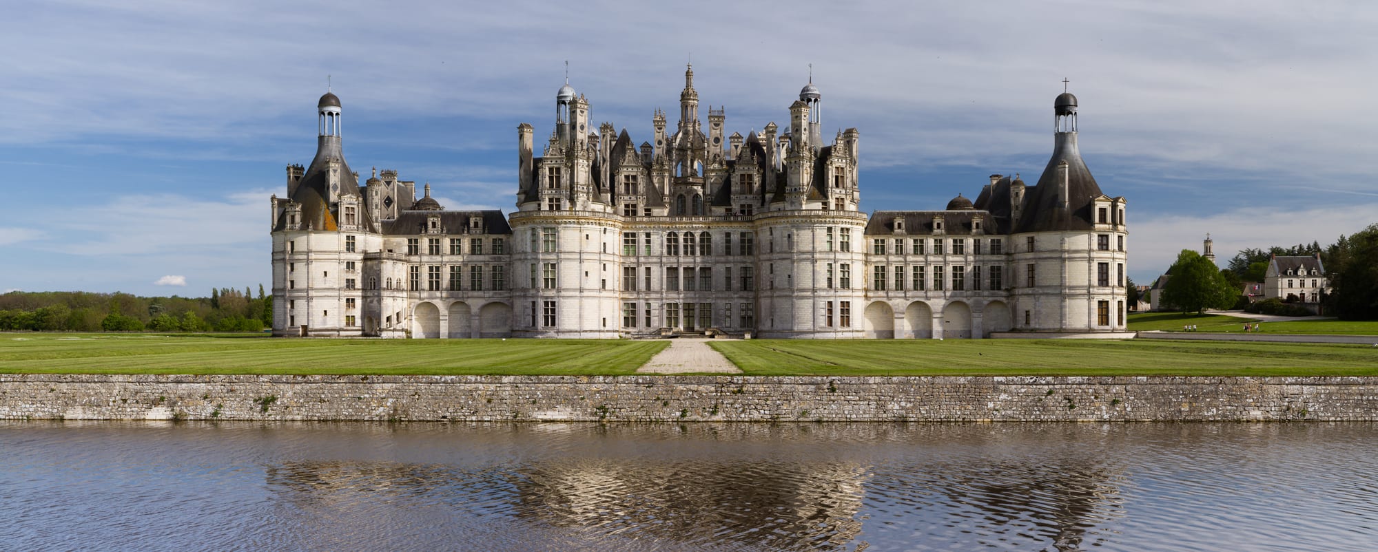 A huge Renaissance château bristling with towers, chimneys, and turrets, reflected in water