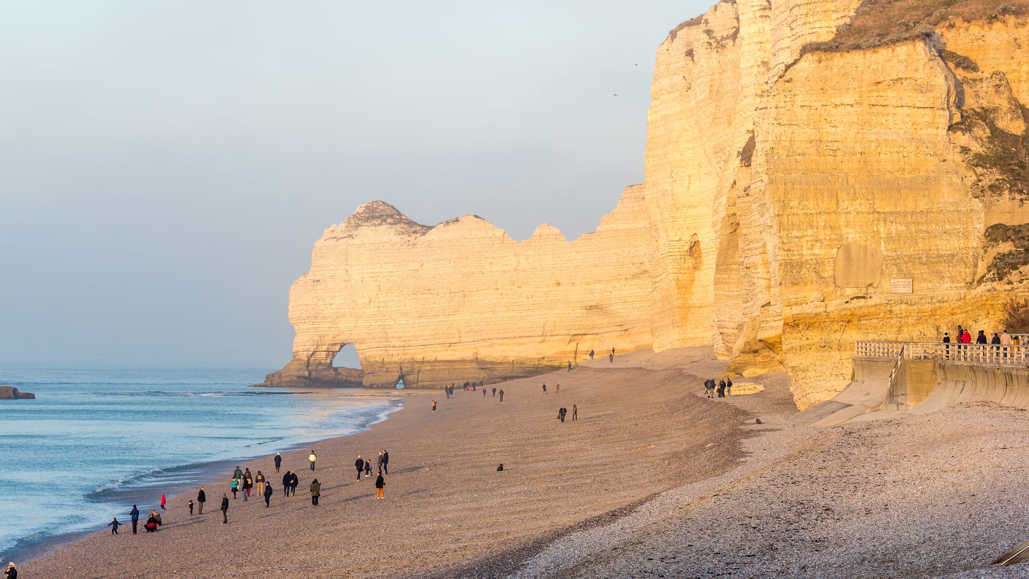 White chalk cliffs with a natural arch and a needle of rock rising from a pebble beach