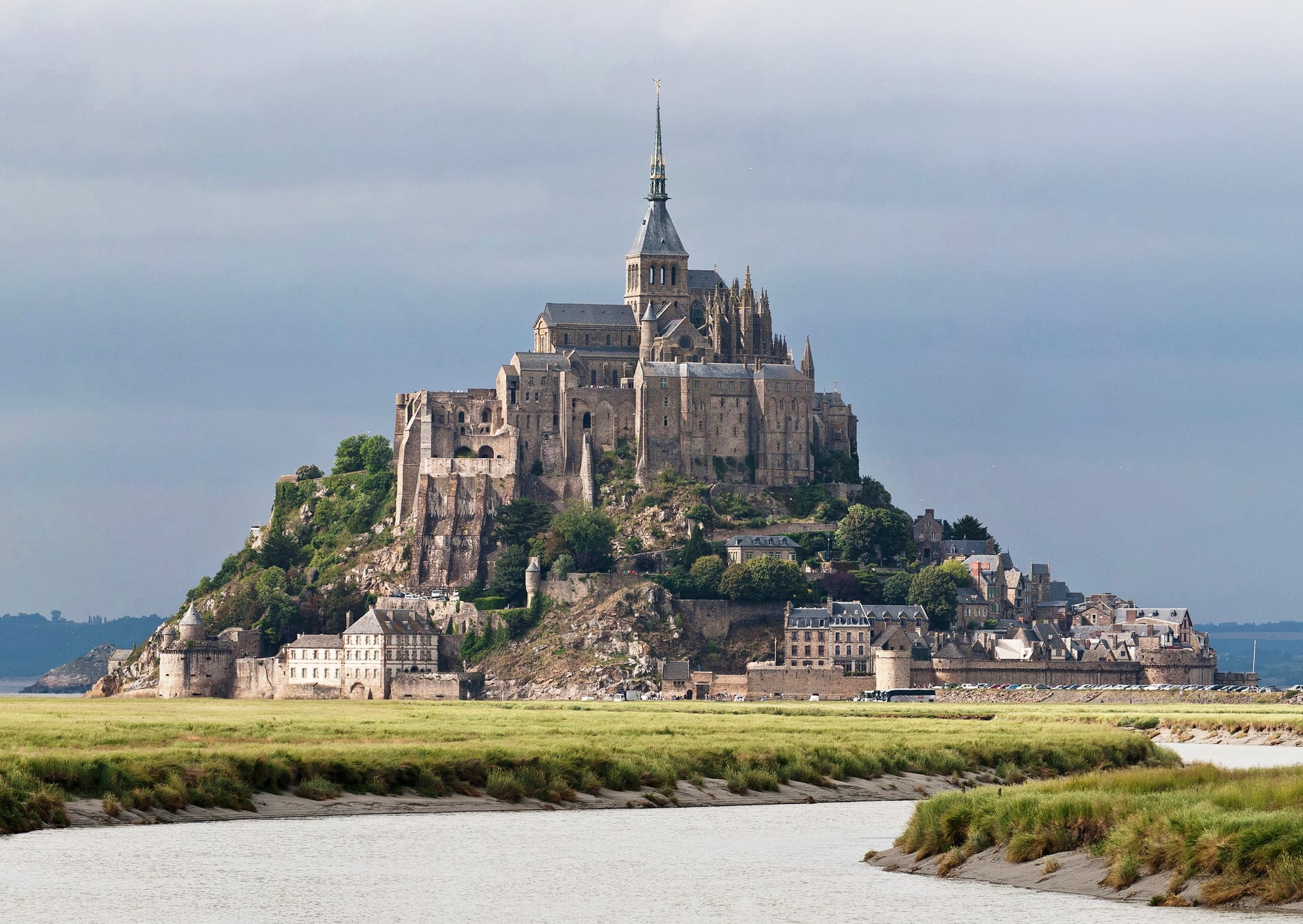 A conical rocky island crowned by a Gothic abbey, rising from tidal flats