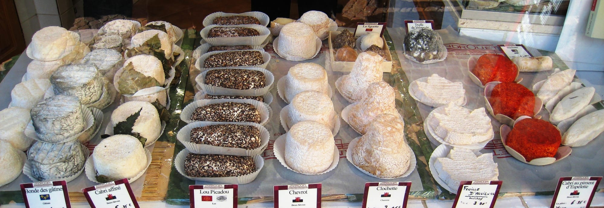 A market stall display of many different cheeses