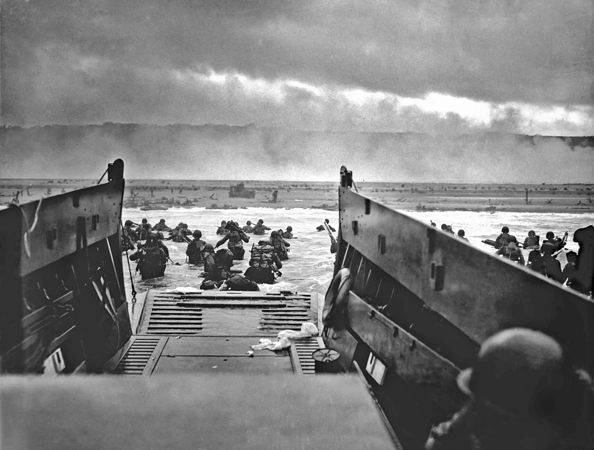 Soldiers wading ashore from a landing craft under fire on a Normandy beach, 6 June 1944