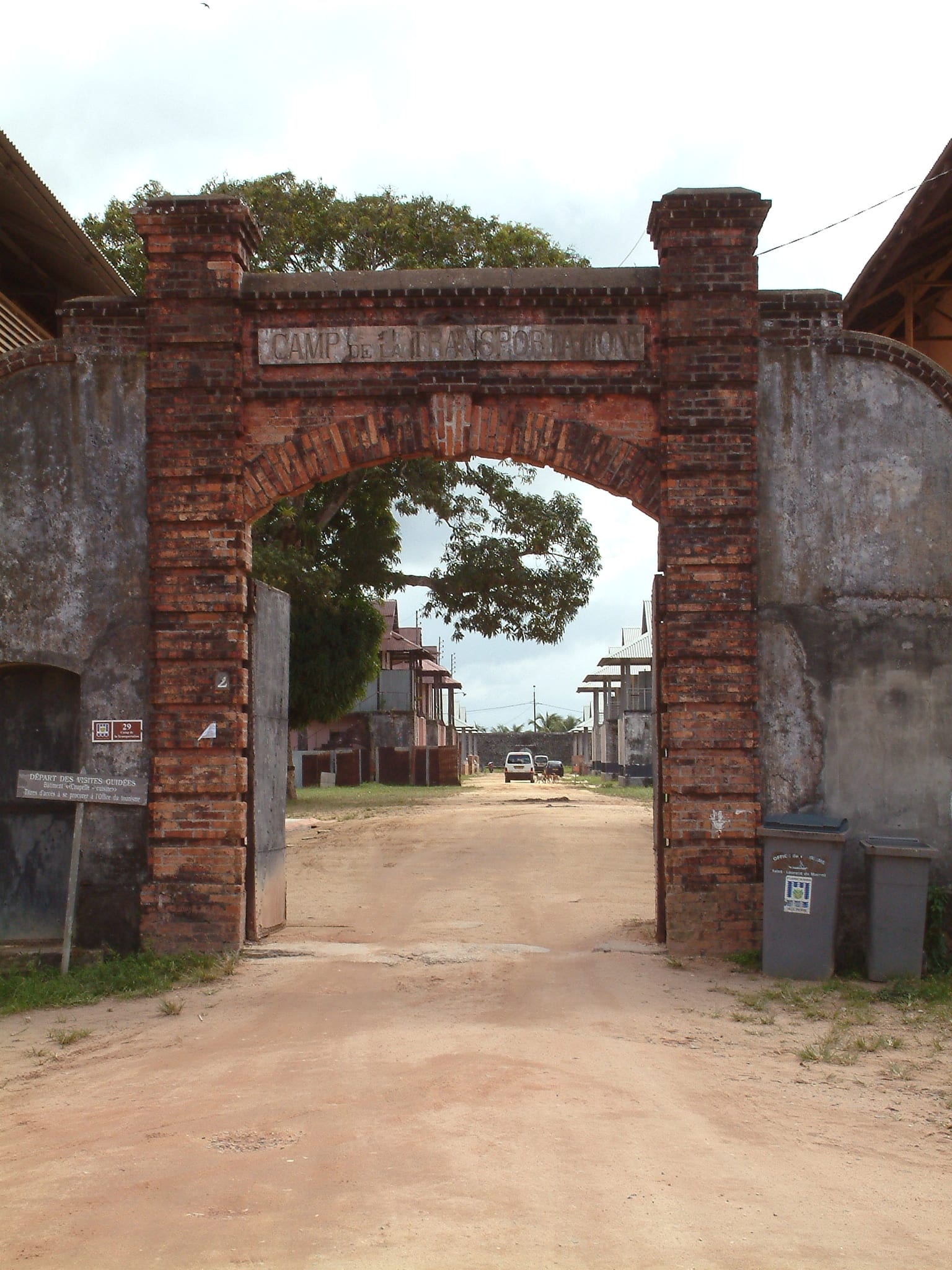 A whitewashed colonial gateway with the words Camp de la Transportation above the arch