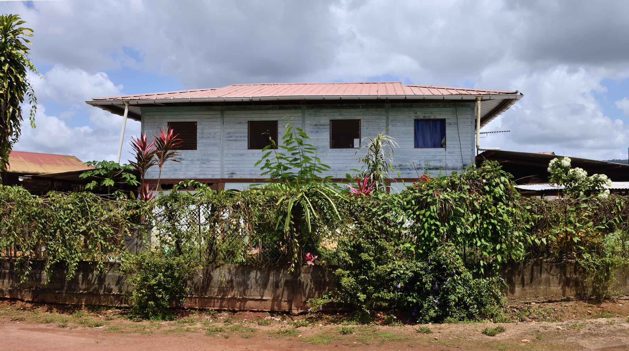 Stilt houses with steep roofs beside a river, forested hills behind