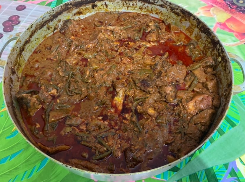 A dark, thick stew in a large pot with visible pieces of meat and vegetables