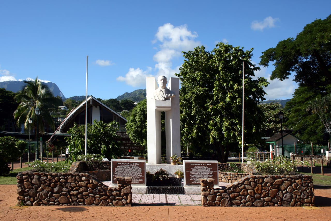 A bronze statue of Pouvanaa a Oopa in a suit, standing on a plinth in a Papeete park