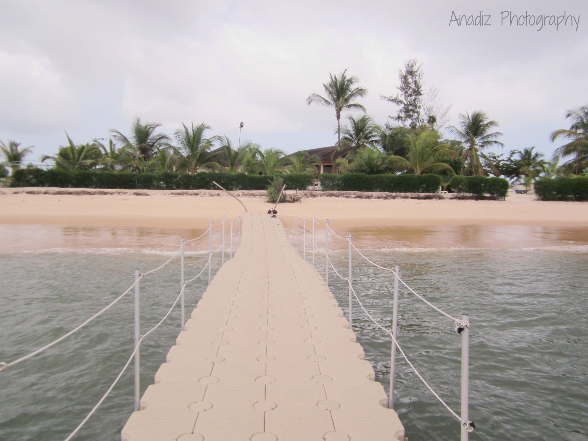 A long empty sandy beach meeting calm water under a hazy sky