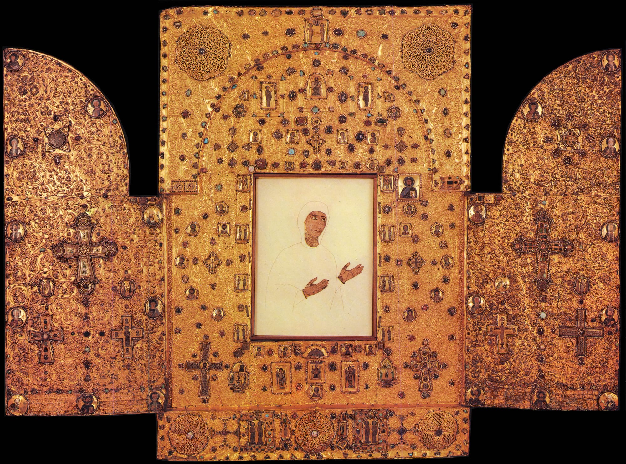 A large gold triptych with two hinged wings, covered in ornate gold work, crosses and small enamel medallions, around a central panel showing the face and hands of the Virgin