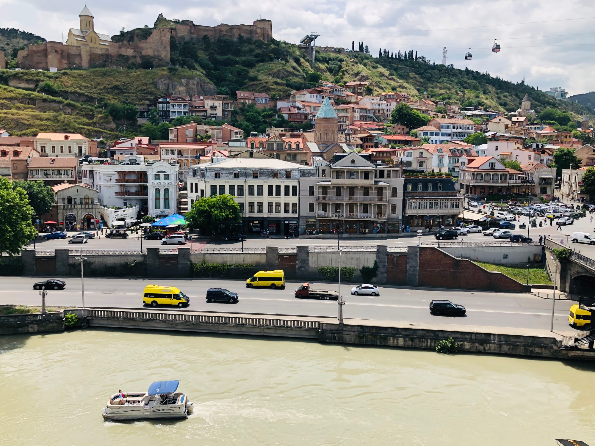 Narrow streets of balconied houses climbing a hill, with church domes and a cable car