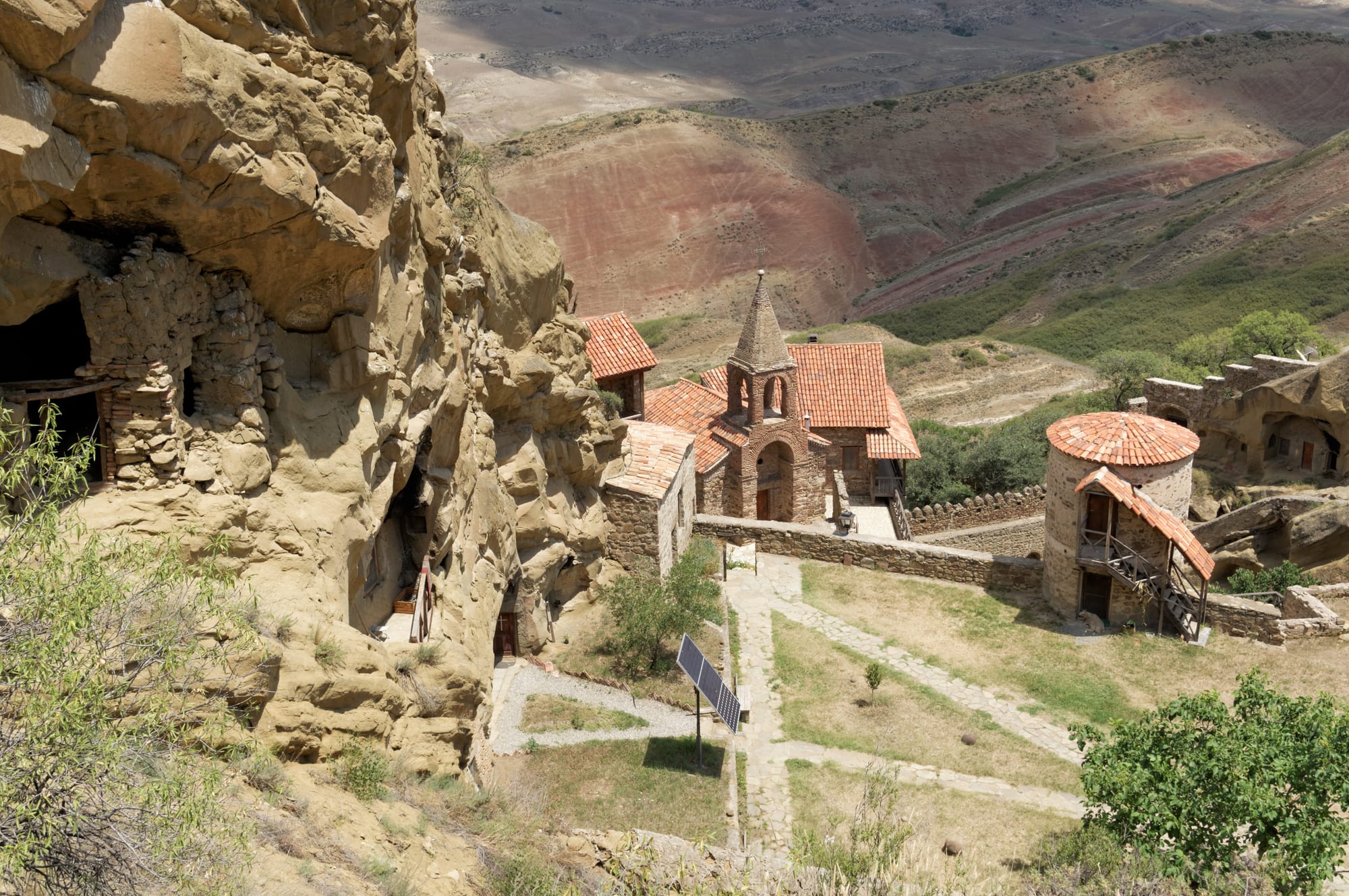 Cave cells and a small monastery complex on a bare ochre desert hillside