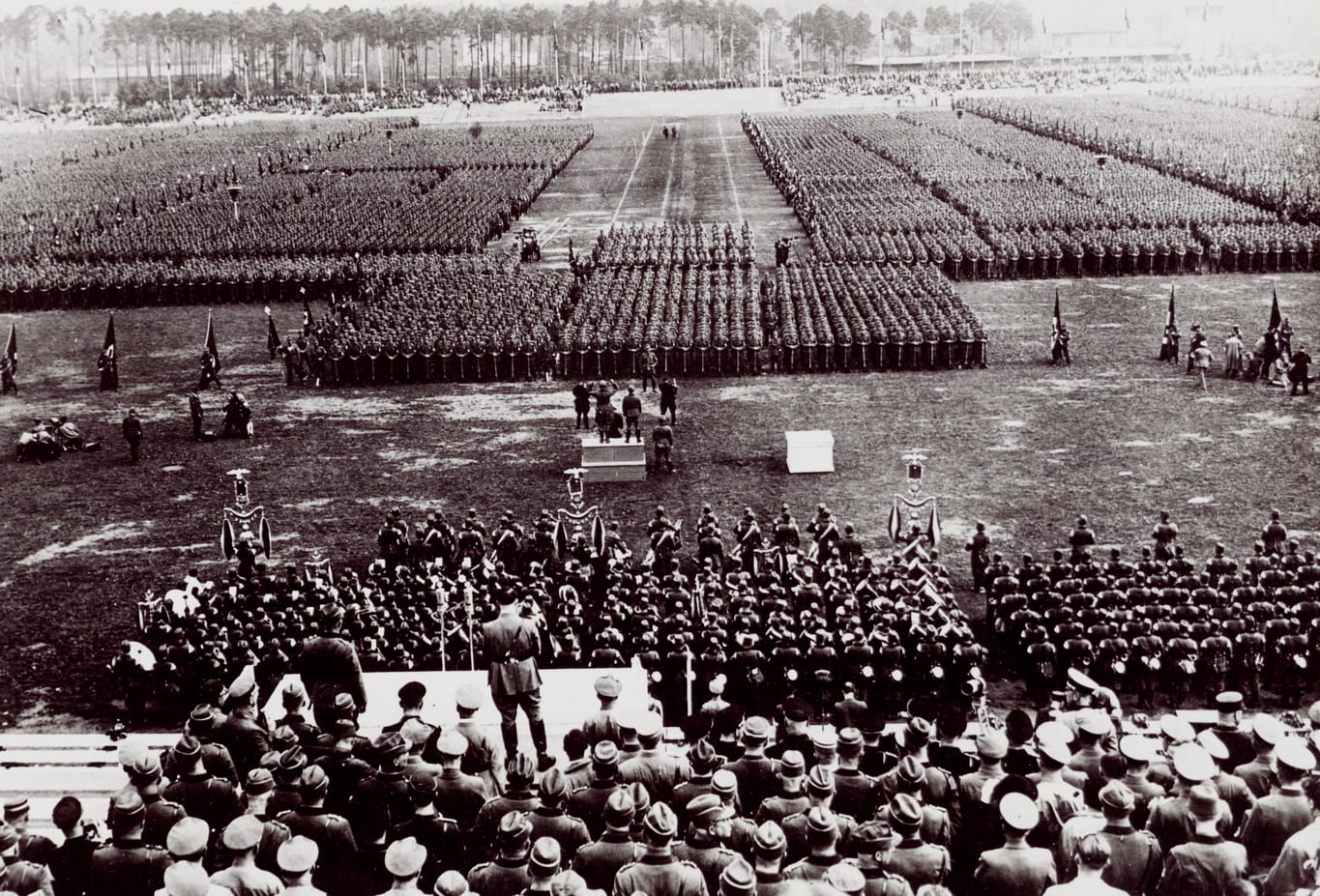 Massed ranks of uniformed men with banners filling a stadium at a Nazi rally