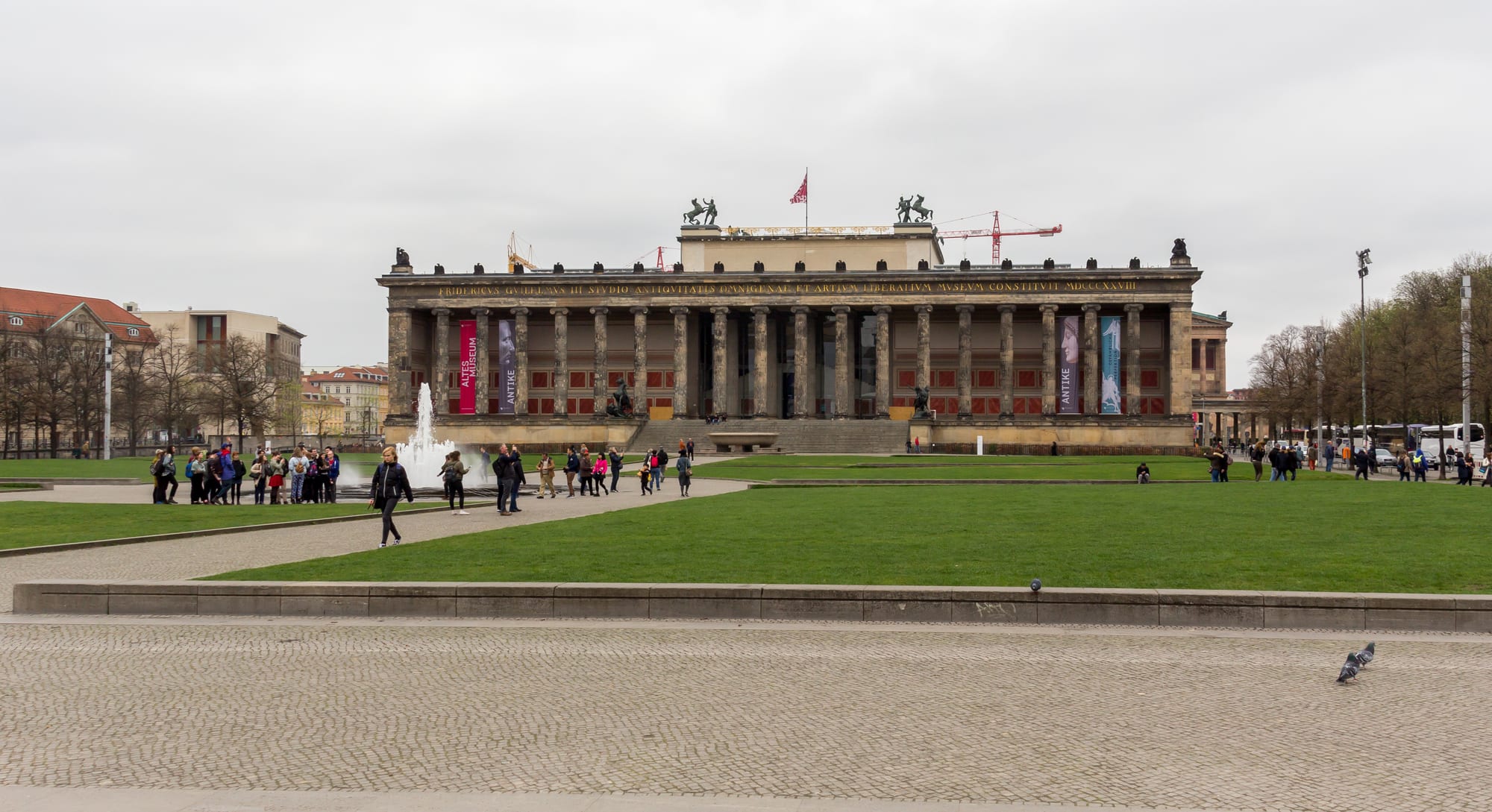 A grand colonnaded museum building beside a river, with a cathedral dome behind