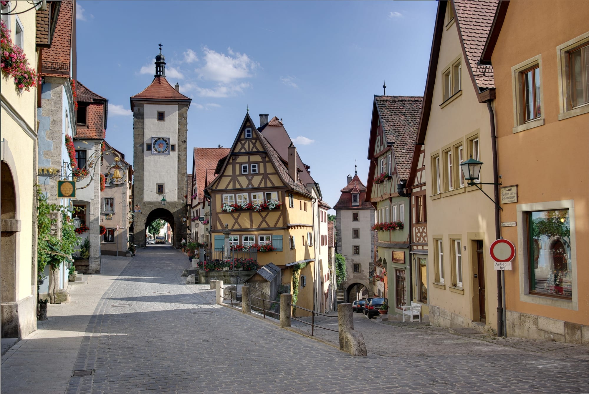 A cobbled lane of half-timbered houses converging on a stone gate tower