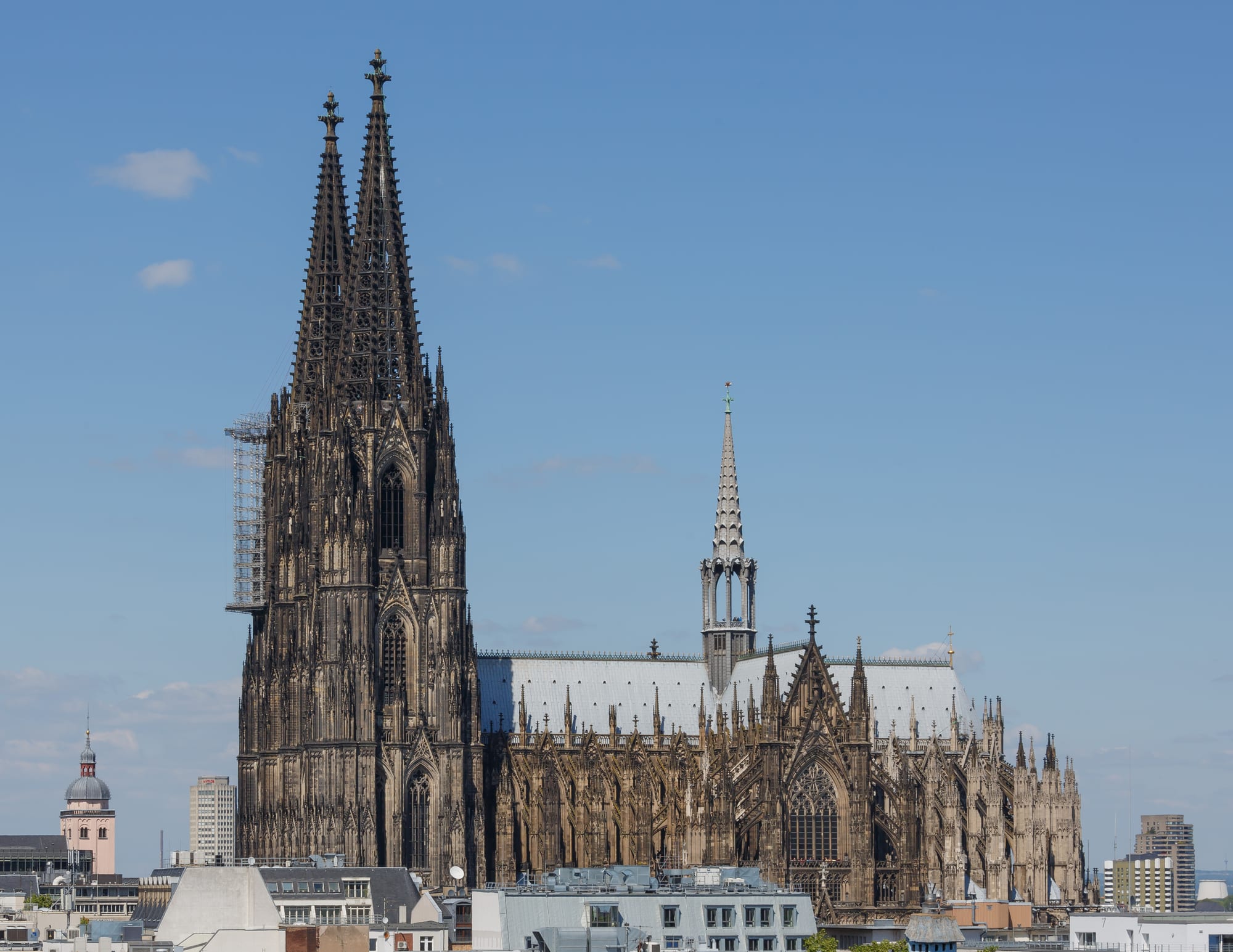 A vast twin-spired Gothic cathedral in dark stone towering over a plaza