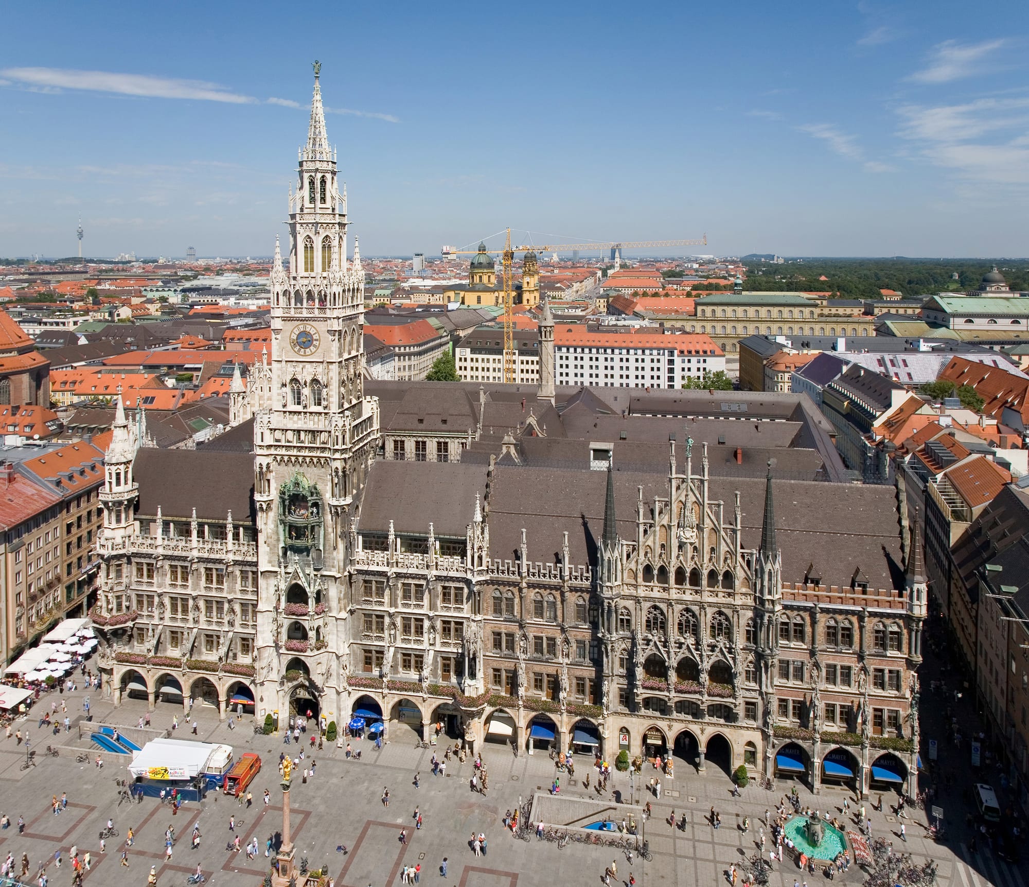 A large neo-Gothic town hall with a tall spire above a busy square