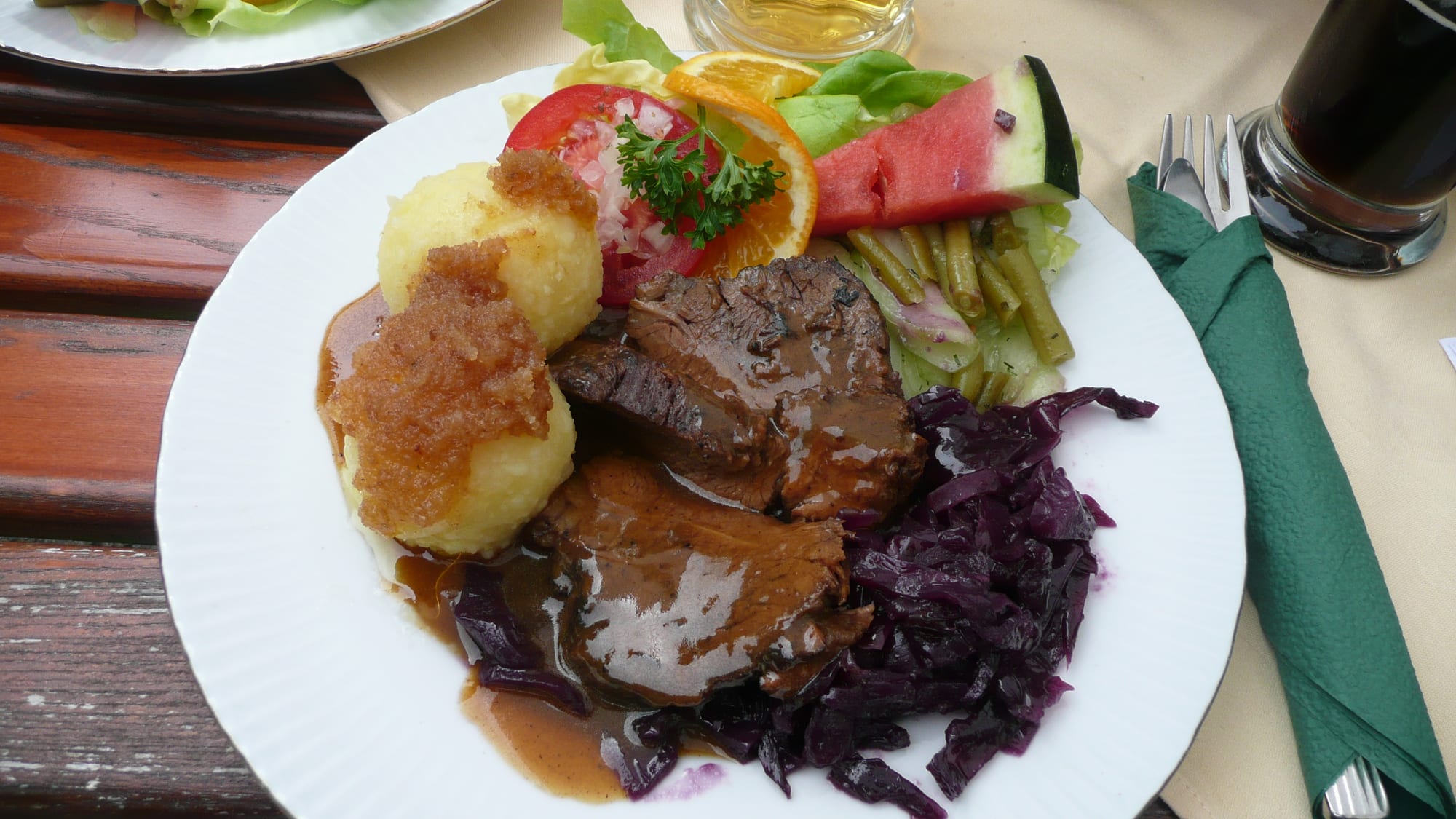 Sliced marinated roast beef served with potato dumplings and red cabbage