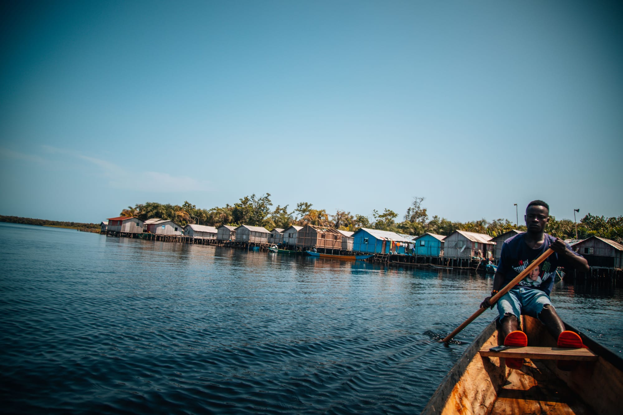 Wooden houses on stilts linked by walkways, standing over still lake water