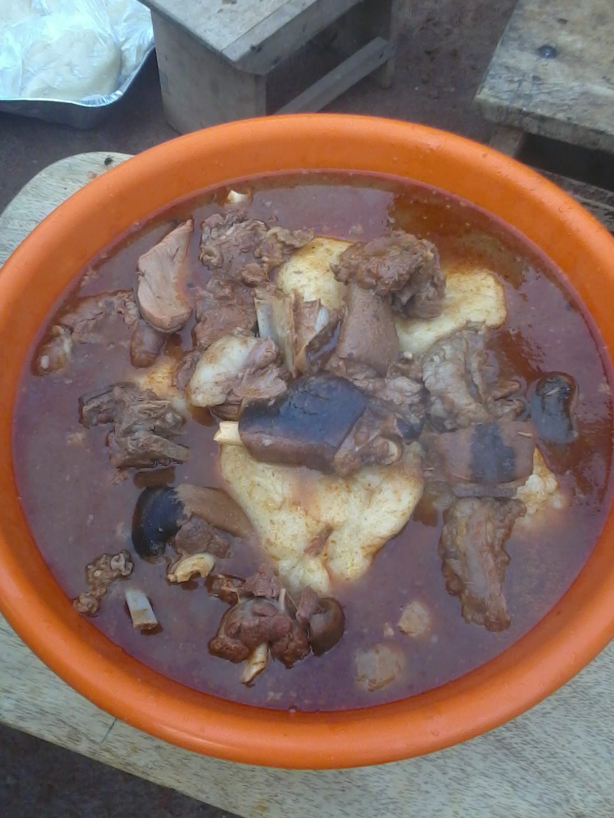 A ball of smooth white dough in a bowl of red soup with meat