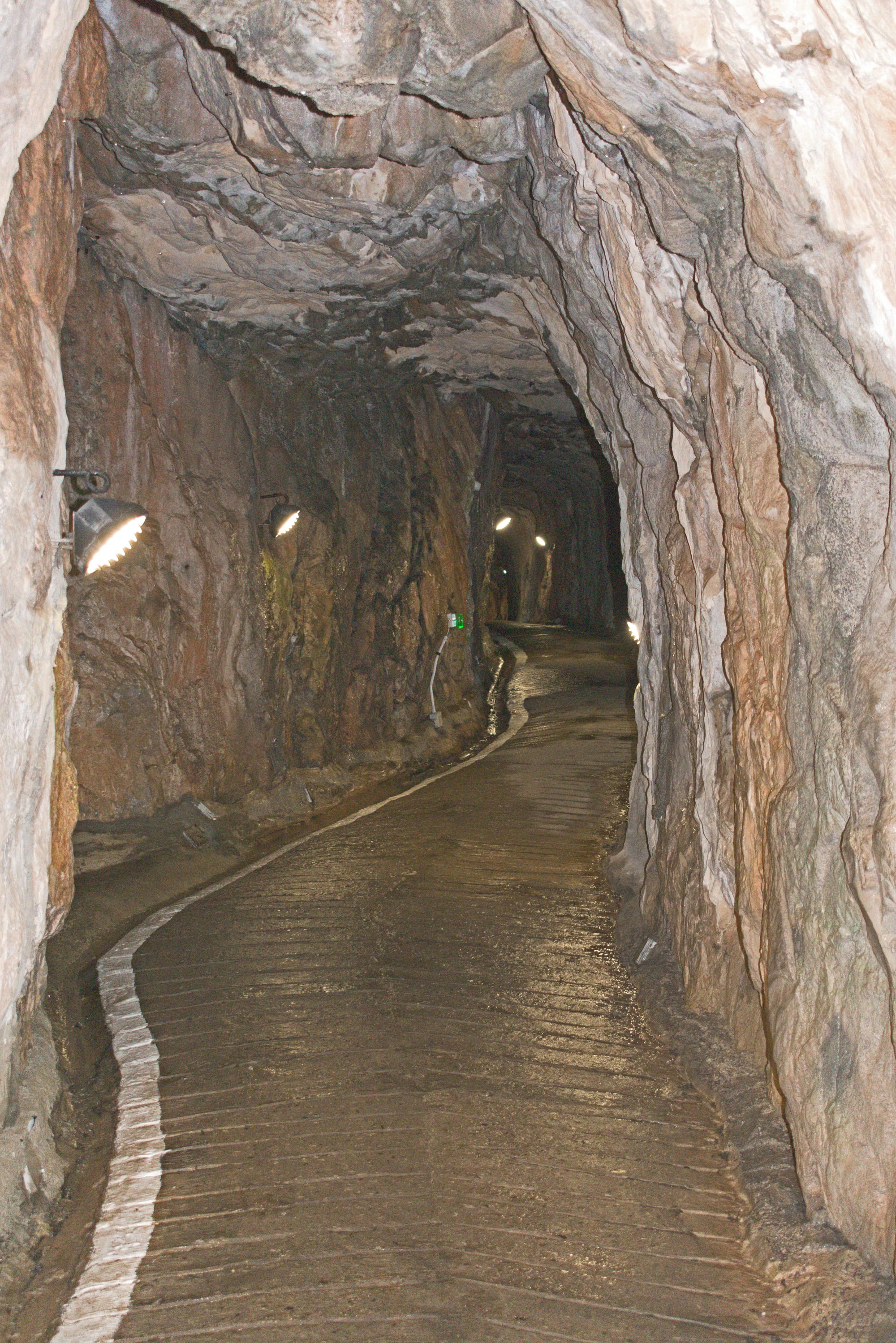 A rough tunnel bored through rock with a cannon embrasure cut in the side wall