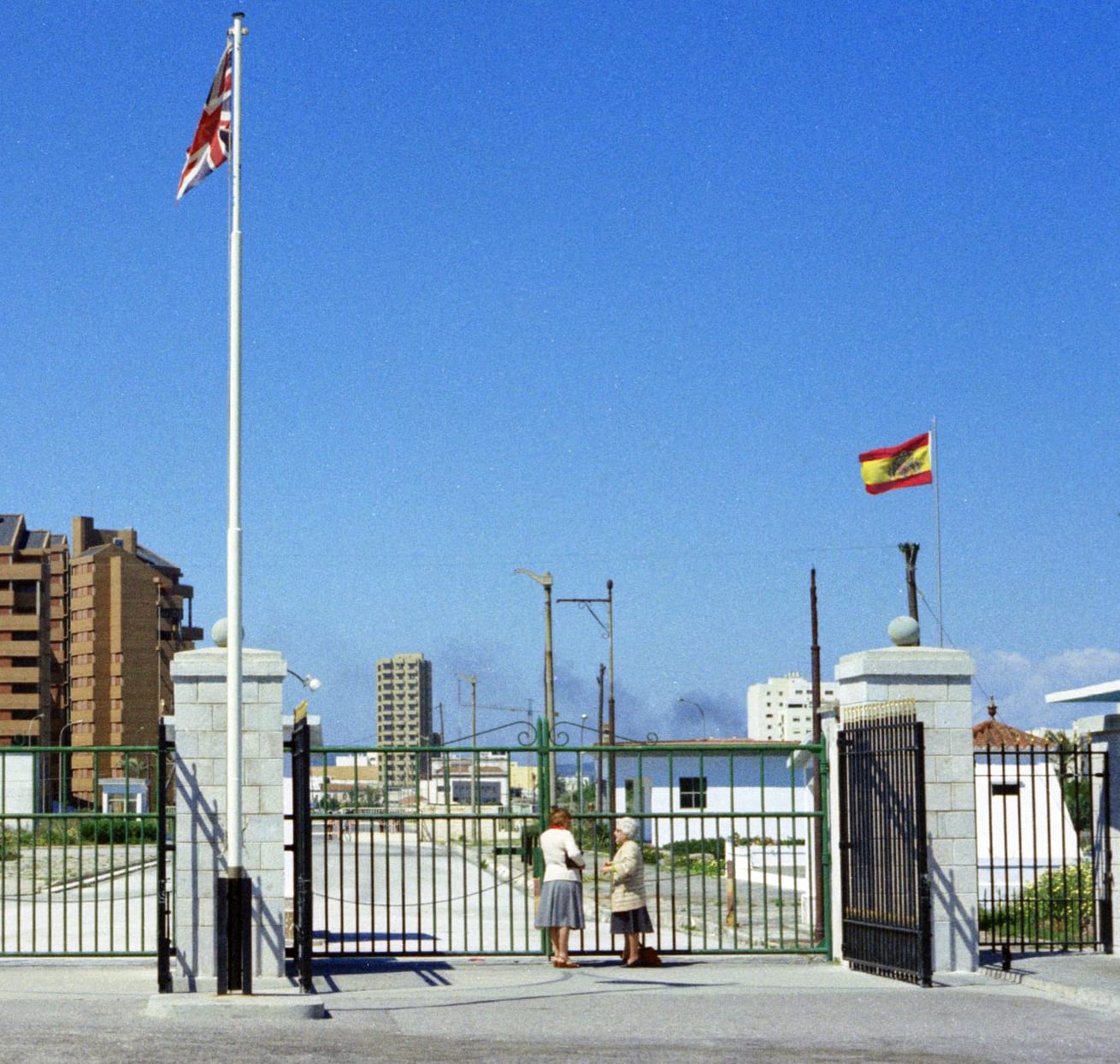 A closed border crossing with fencing and a lone building, seen in 1977