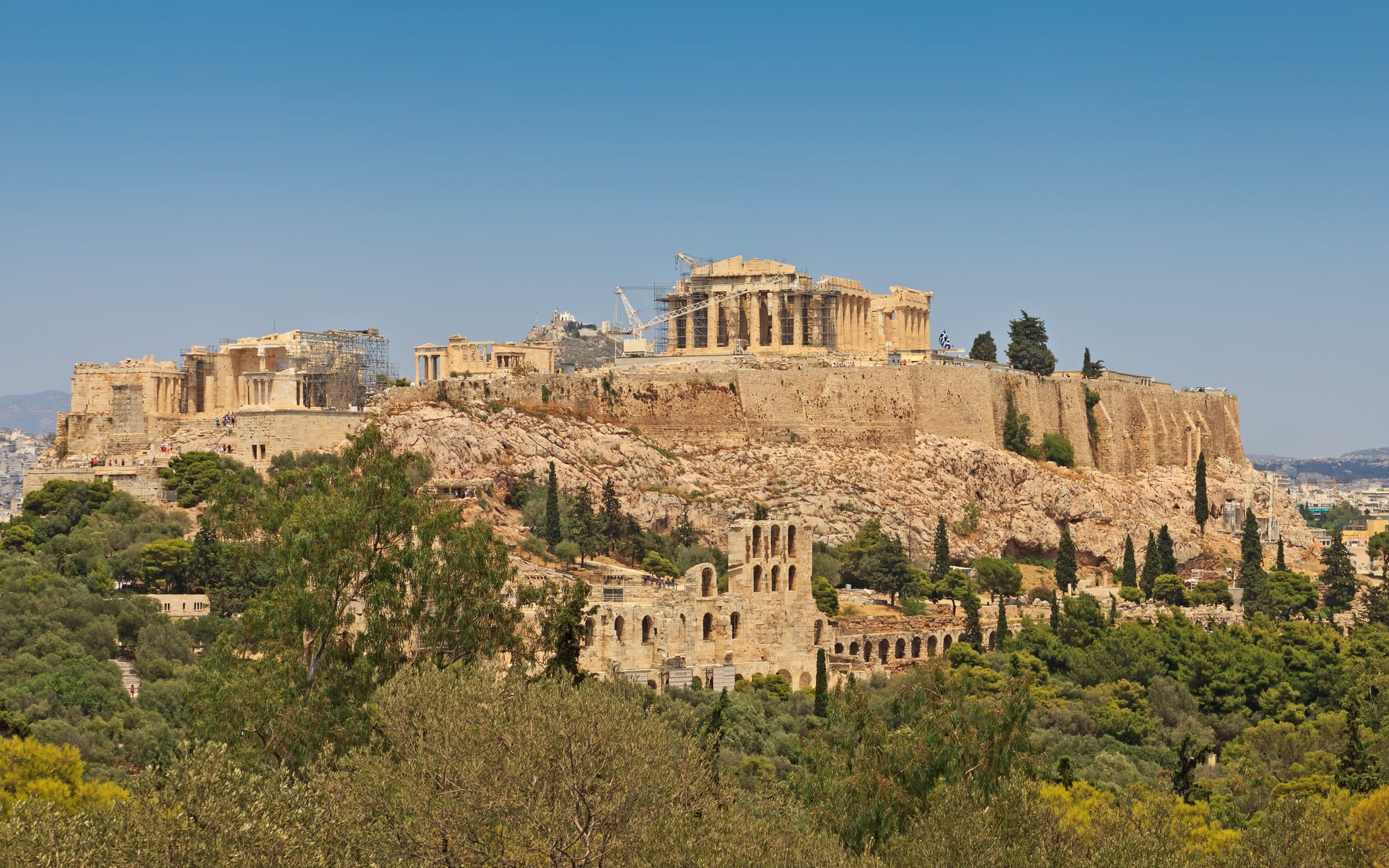 A marble temple ruin on a rocky hilltop above a sprawling white city