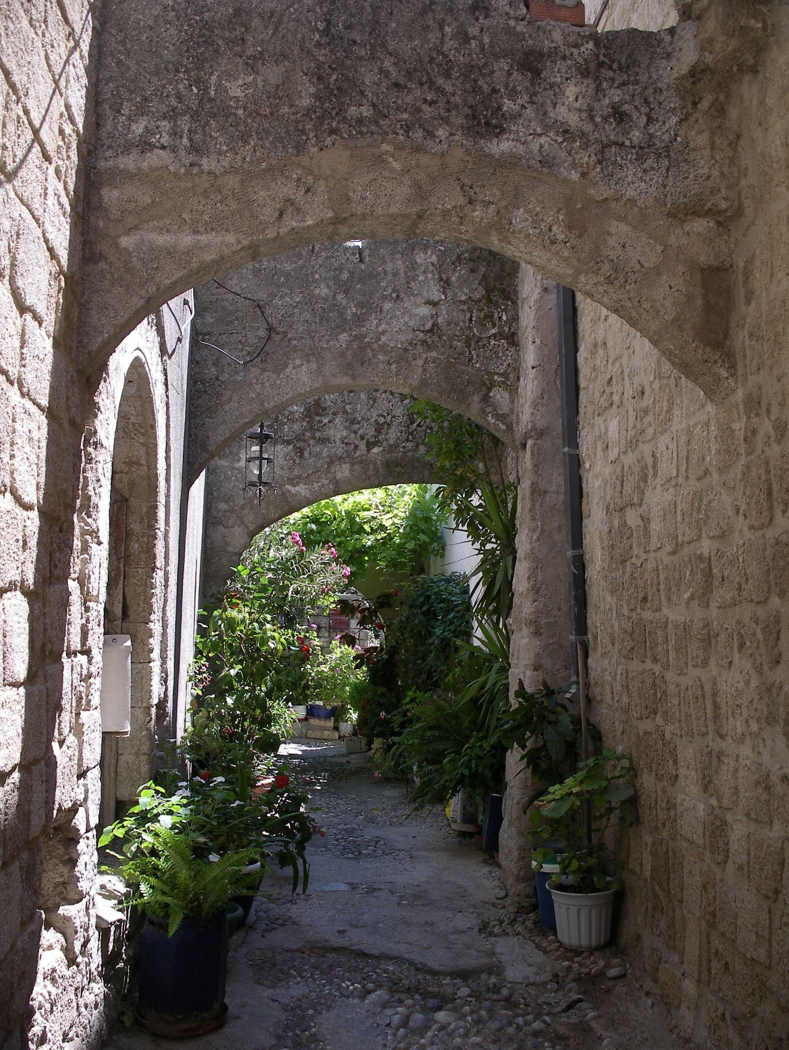 A cobbled medieval street of honey-coloured stone buildings and archways