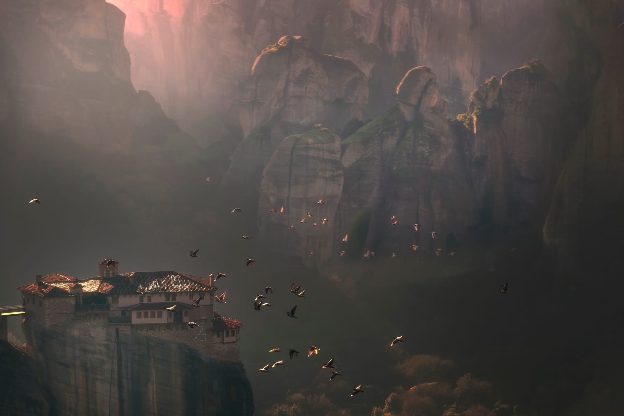 A stone monastery perched on top of a sheer rock pinnacle, with more pillars behind
