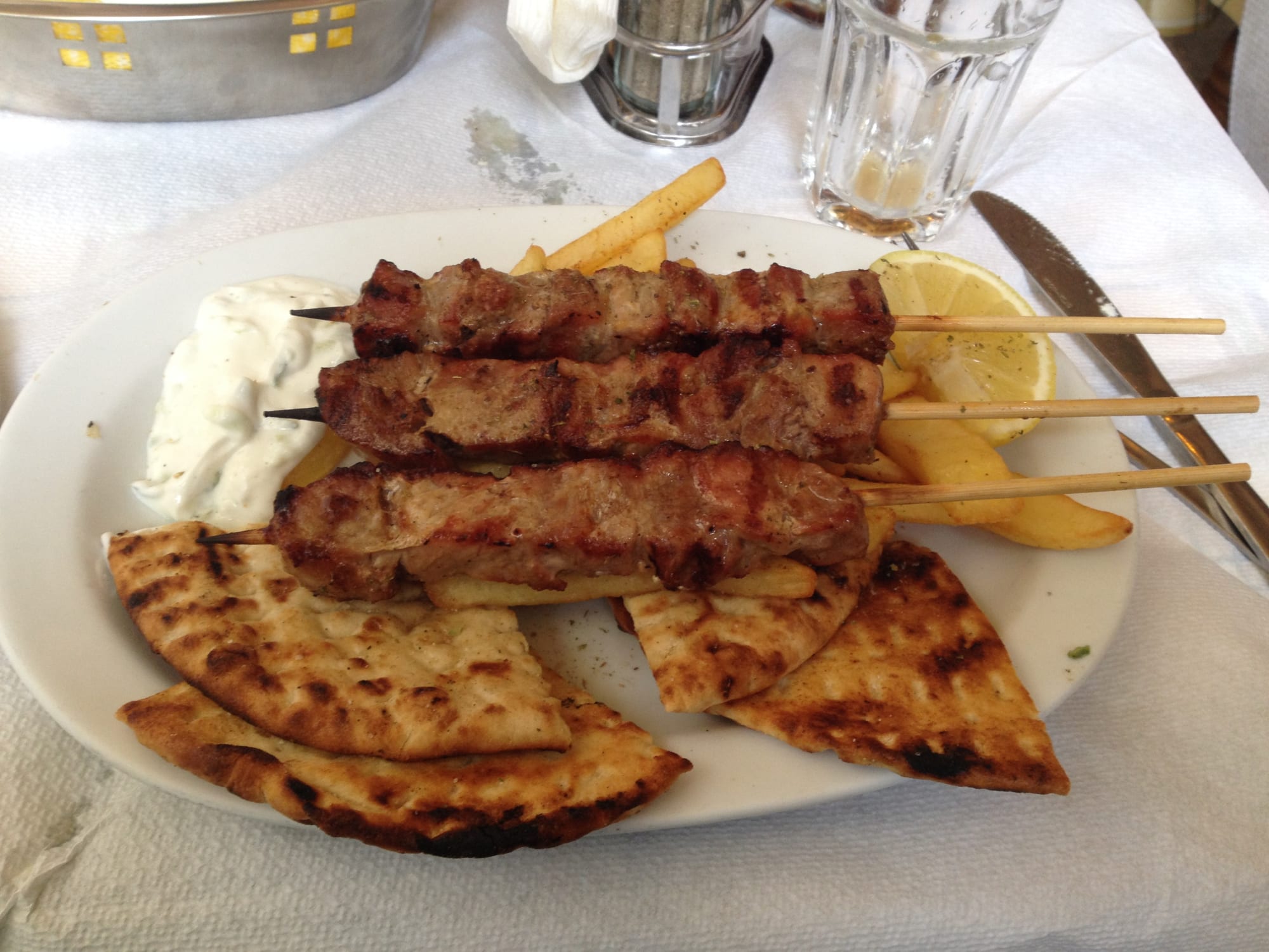 Grilled meat skewers with pita, tomato and onion on a plate