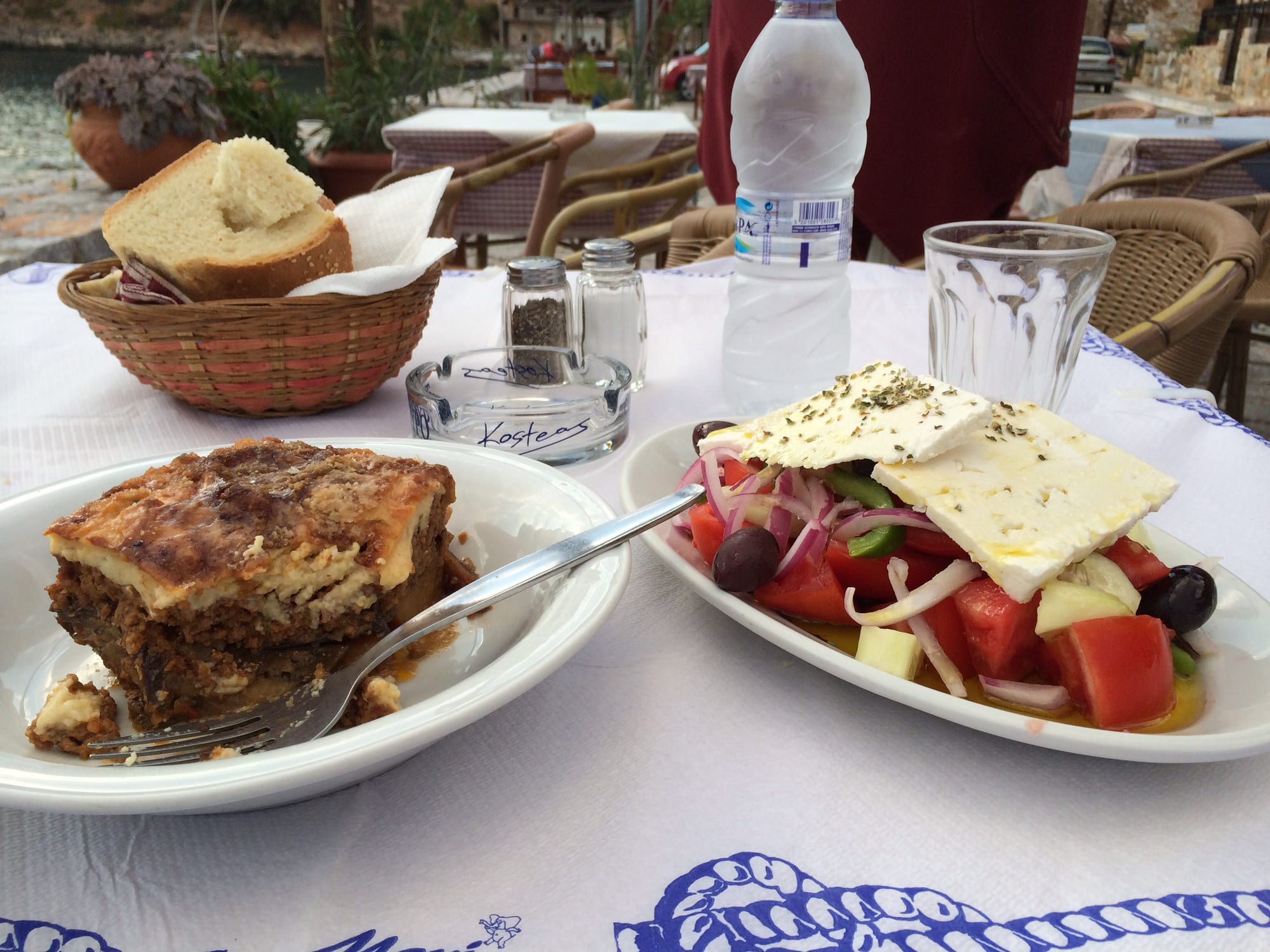 A baked casserole dish with layers of aubergine and a golden top, served with salad