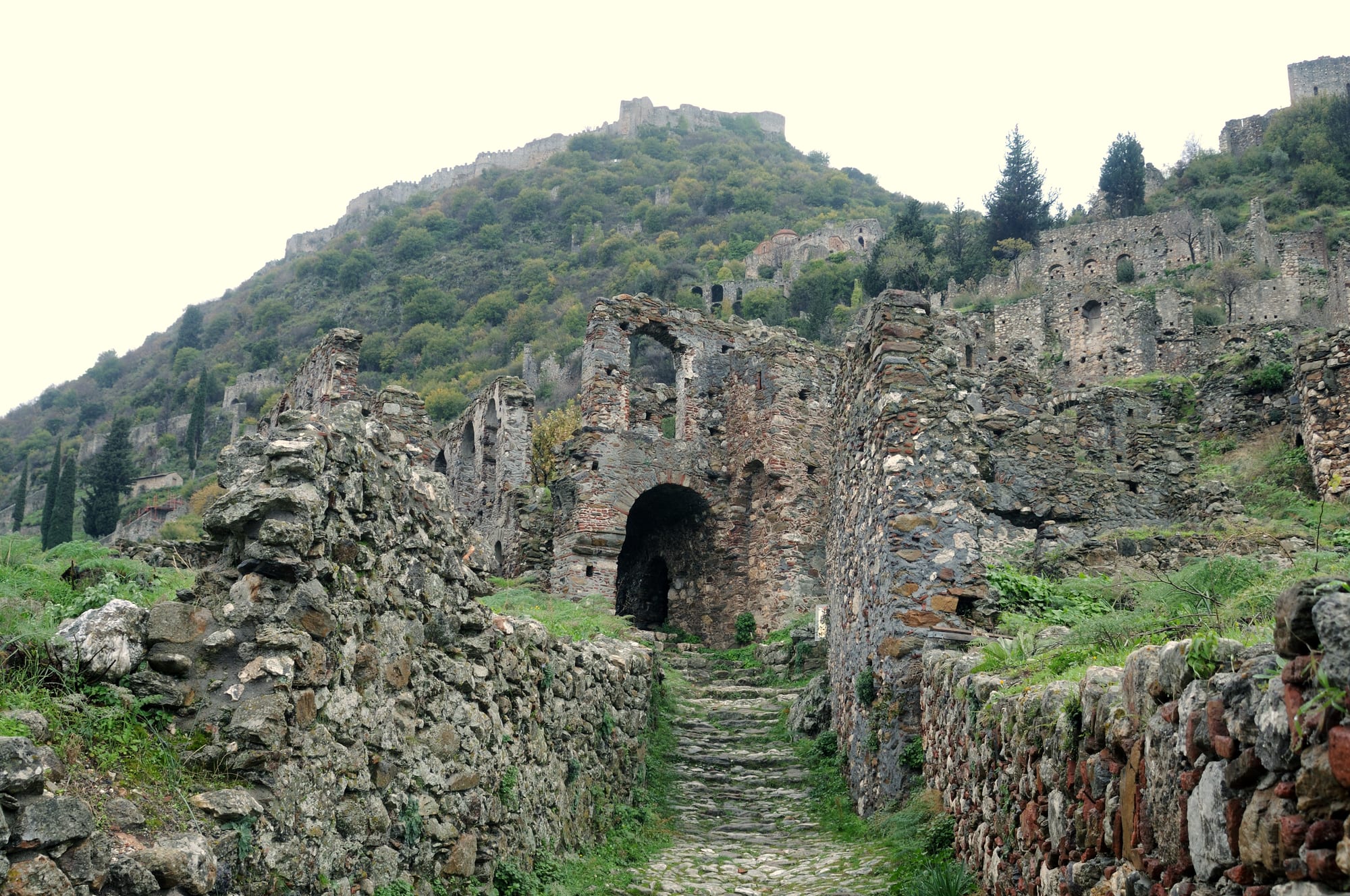 Stone churches and houses of a ruined Byzantine hill town below a castle